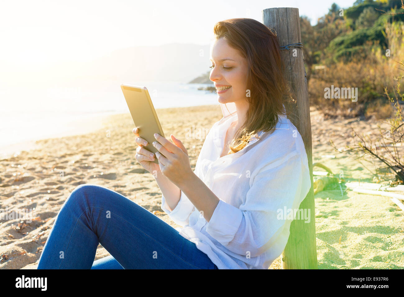 Frau mit einem digitalen Tablet am Strand Stockfoto