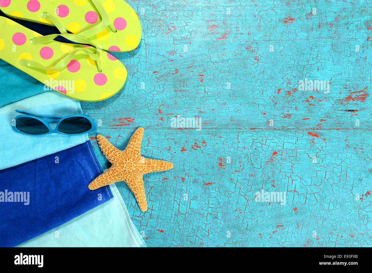 Strand-Handtuch, Sonnenbrille, Seesterne und Flip flops über bemalte hölzerne Planken Stockfoto