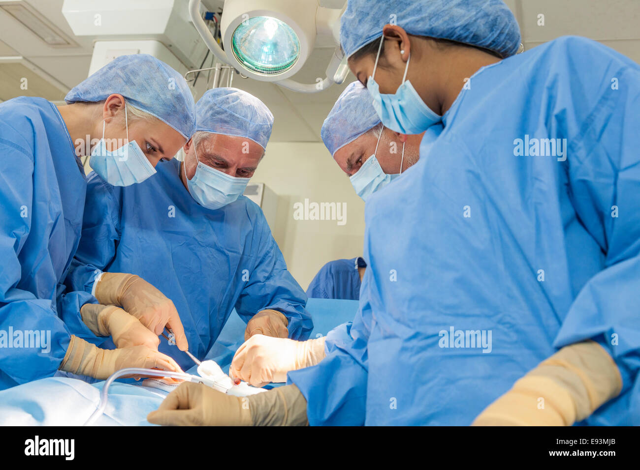 Ein Team von interracial Ärzte männlichen & weiblichen Chirurgen in der Chirurgie bei einem Patienten mit verschiedenen medizinischen Geräten in Betrieb Stockfoto