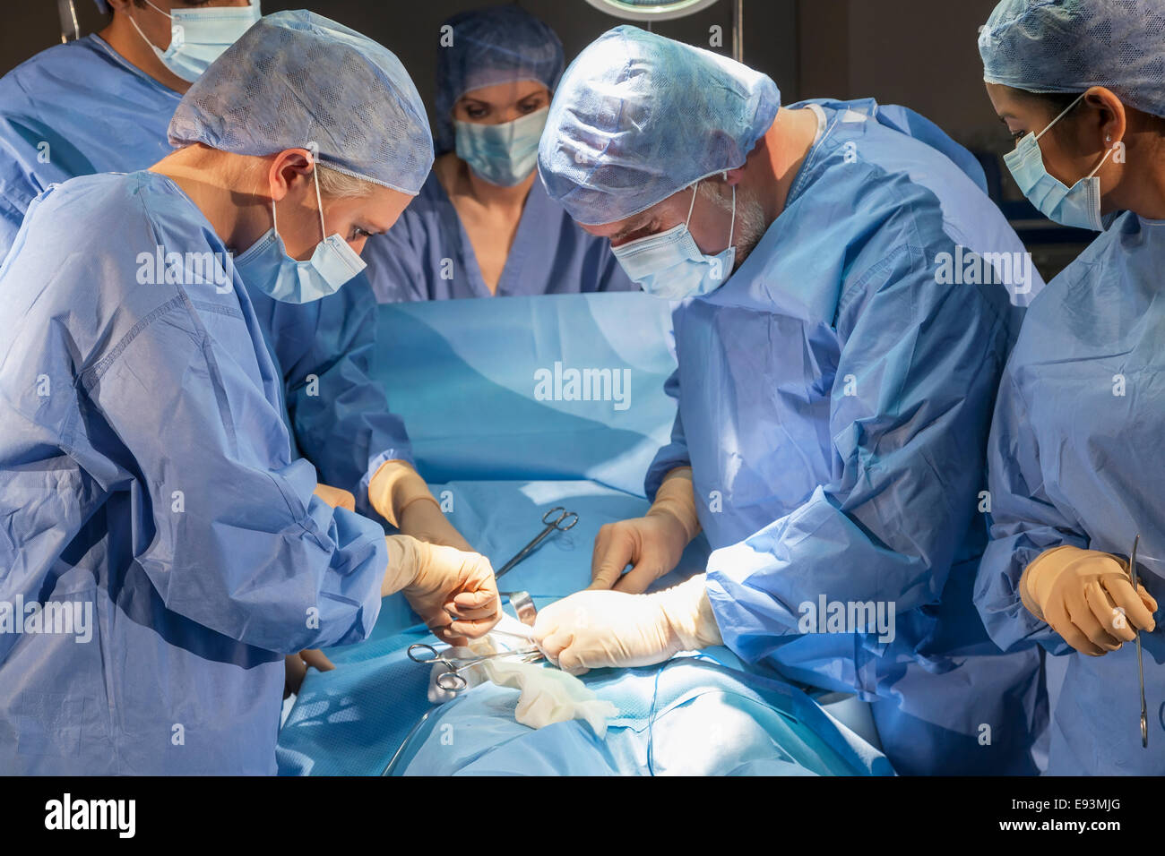 Ein Team von interracial Ärzte männlichen & weiblichen Chirurgen in der Chirurgie bei einem Patienten mit verschiedenen medizinischen Geräten in Betrieb Stockfoto