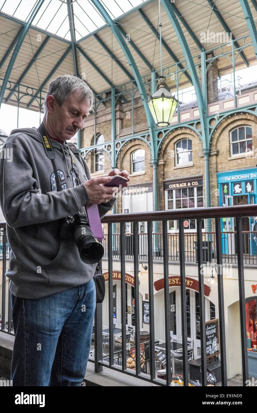Mann mit Kamera stoppt zu mobil telefonieren im Londoner Covent Garden Stockfoto