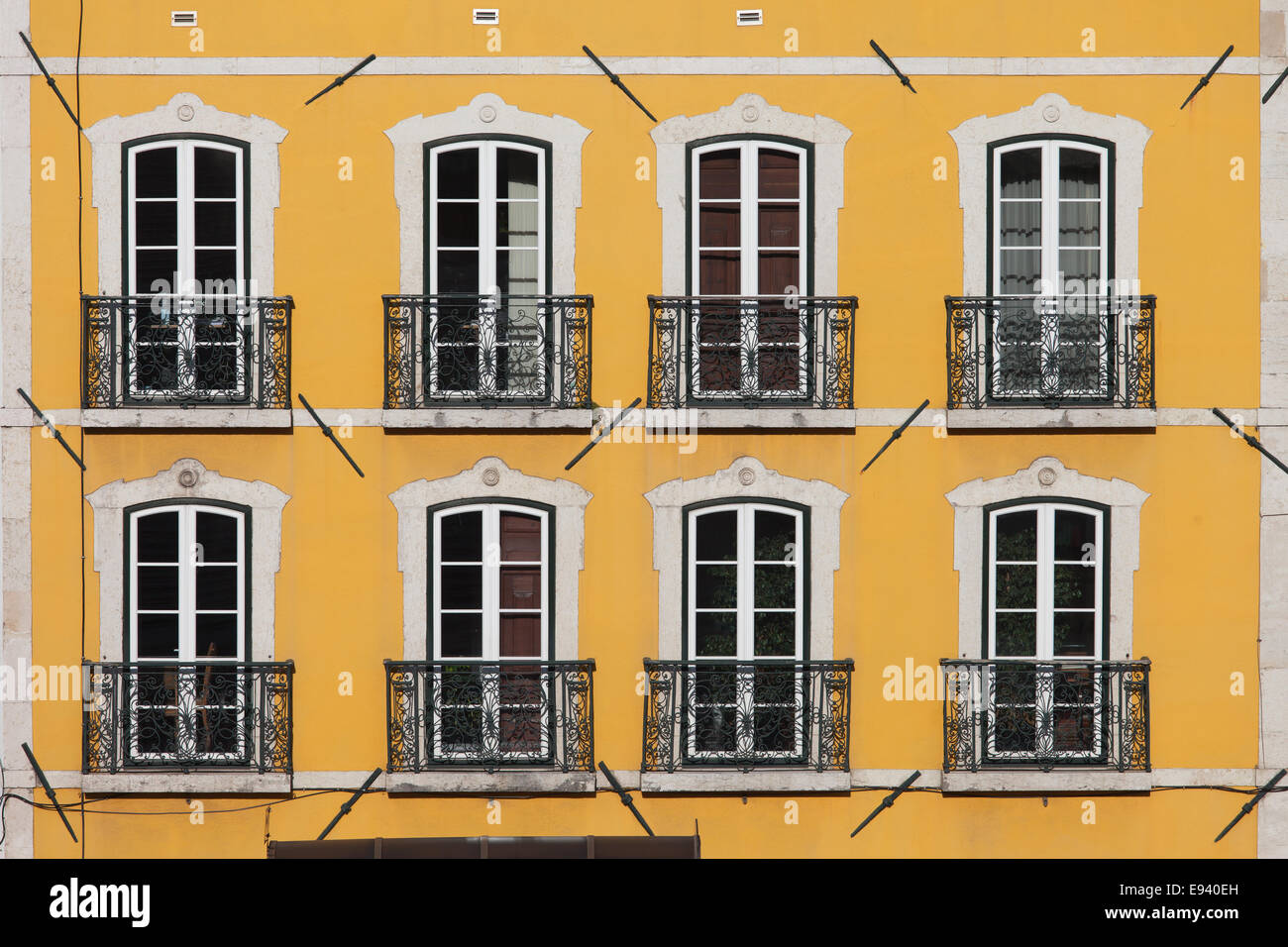 Traditionelles Gebäude mit gelber Fassade und große Fenster mit Balconets in Lissabon, Portugal. Stockfoto