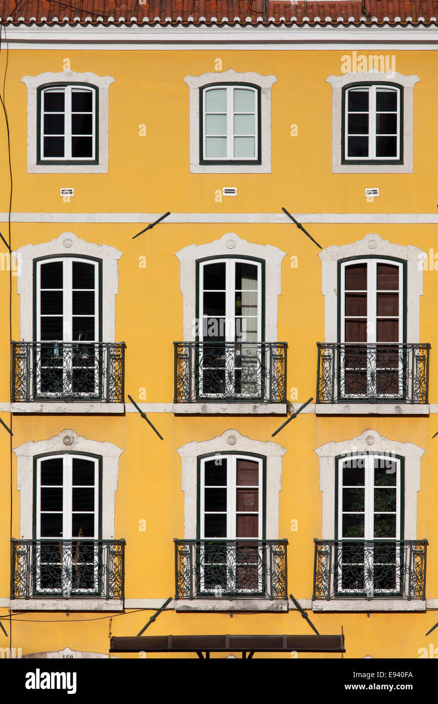 Traditionelles Gebäude mit gelber Fassade und große Fenster mit Balconets in Lissabon, Portugal. Stockfoto
