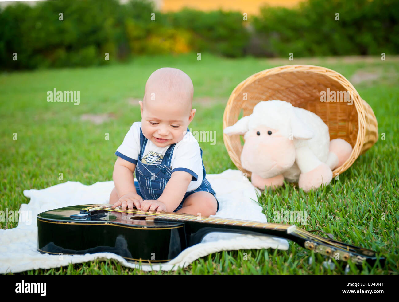 Der kleine Junge mit der Gitarre auf dem Rasen Stockfoto