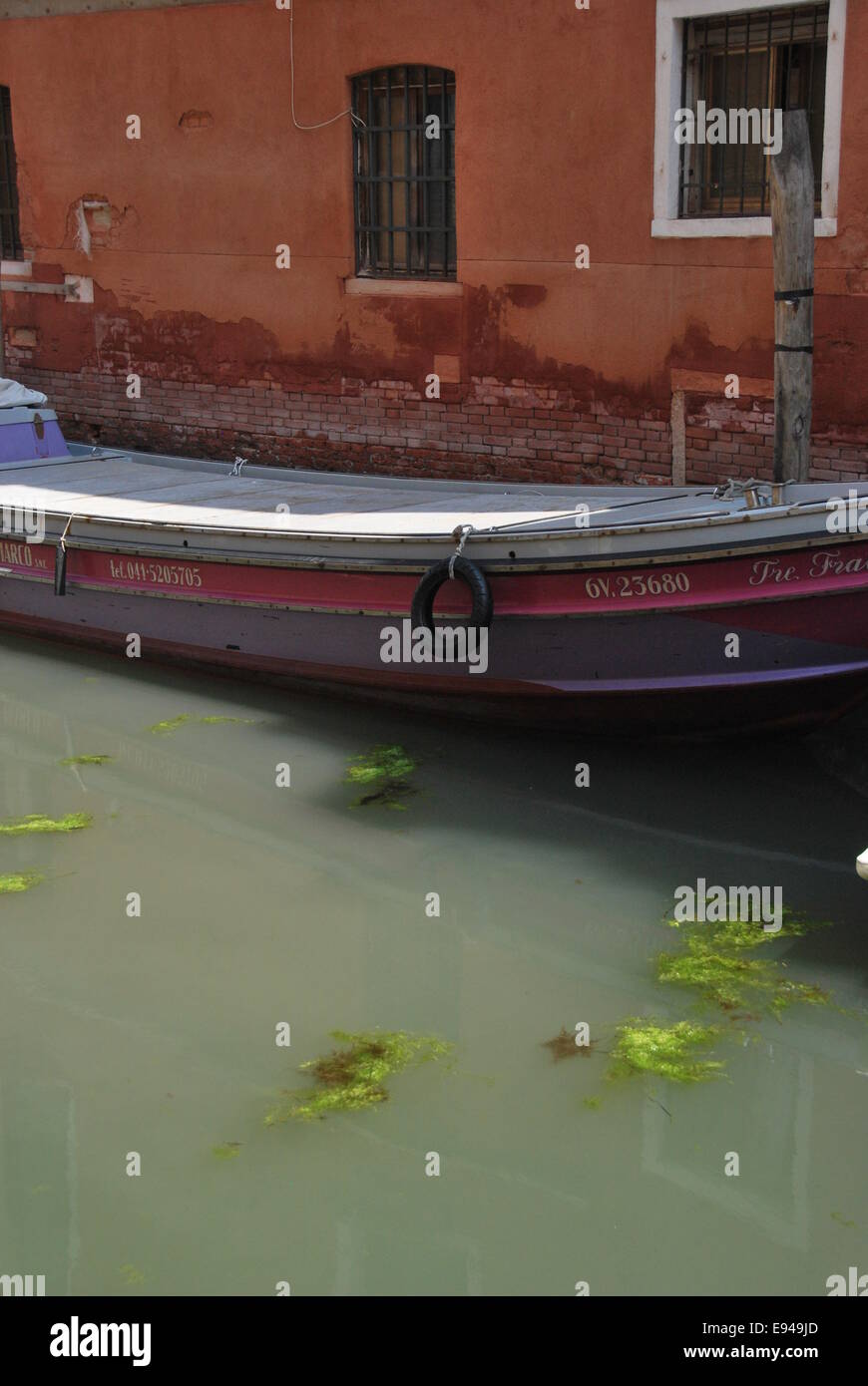 Italien. Venedig. Kanal-Szene. altes Boot. abgenutzte Holz, Mauerwerk bröckelt.  Reflexionen, Bewegung. zu beruhigen. Stockfoto