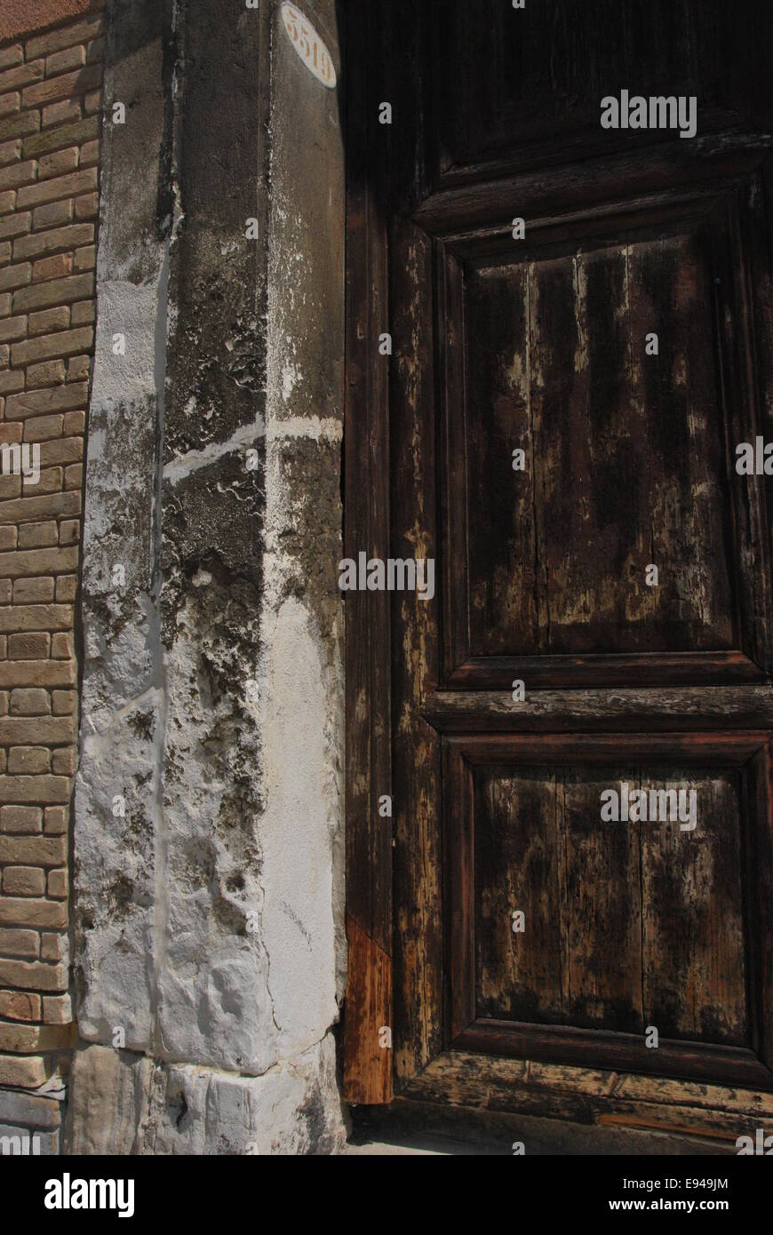 Italien. Venedig. alte Tür. abgenutzte Holz, alte. Steinsäule, moderne Ziegel. Stockfoto
