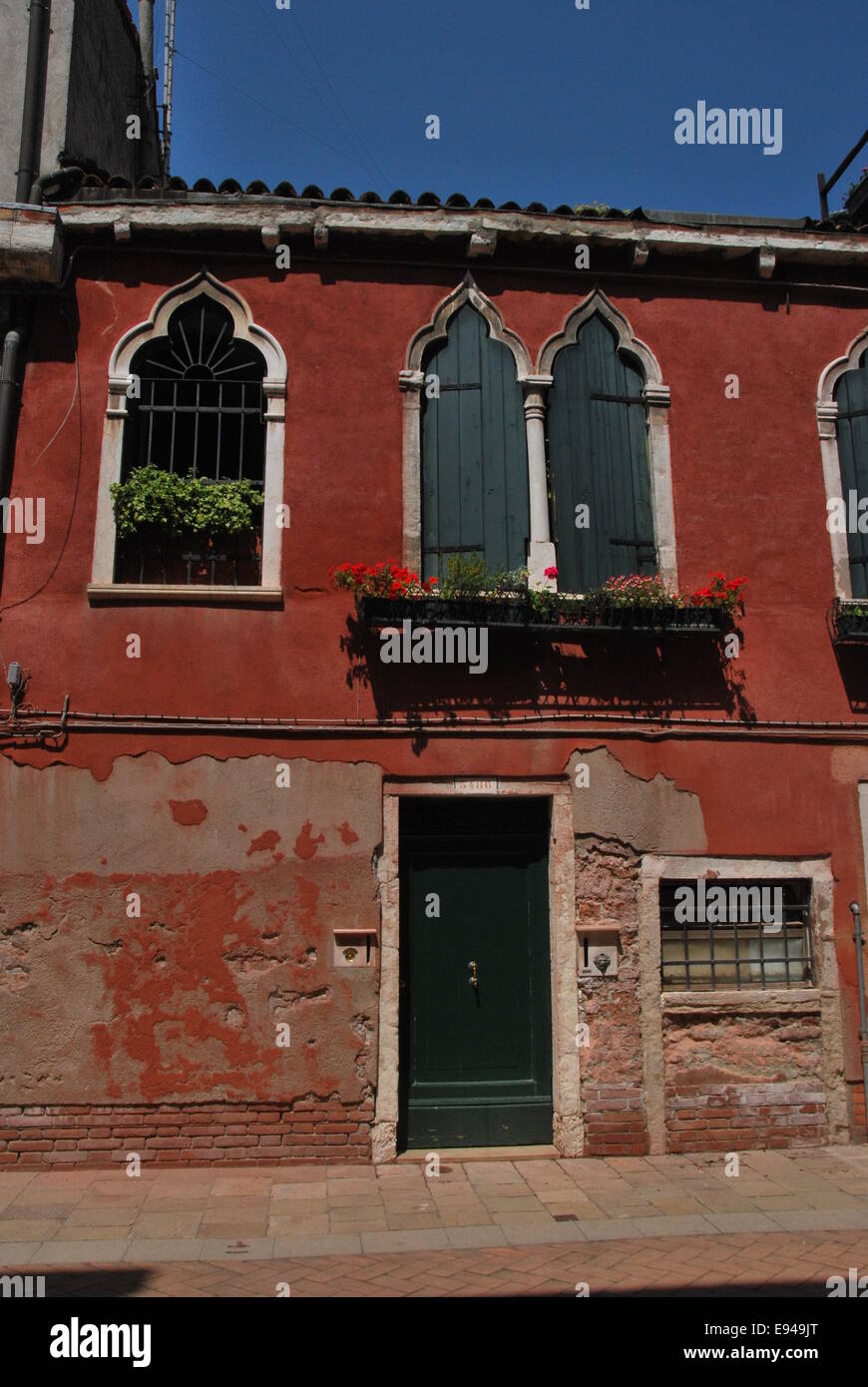 Italien. Venedig. Tür. rot gestrichene Wände. grüne Tür. Fenster-Box. Hof. Sonnenschein, dekorative Fenster Stockfoto