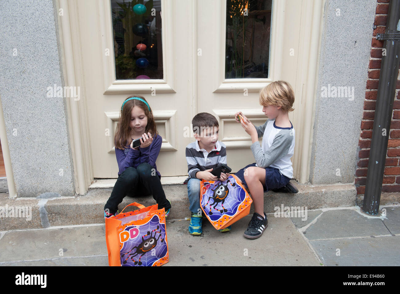 Drei Kinder mit Handys an ein Straßenfest in der South Street Seaport, kurz vor Halloween. Stockfoto
