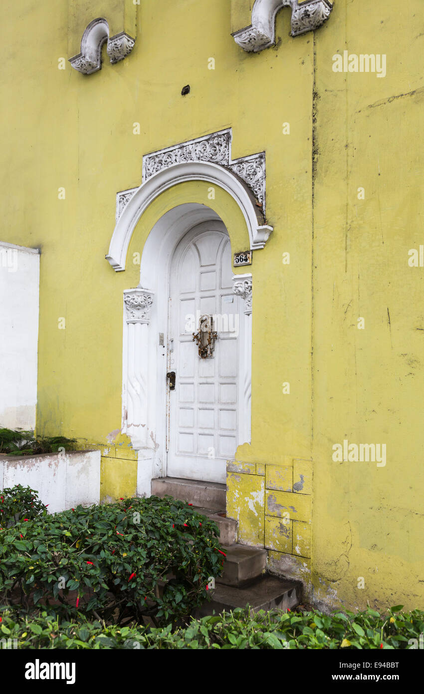 Weiße Tür- und Stuck mit abblätternden Lack in einer gelben Wand eines vernachlässigten vorstädtischen Kolonialhauses im Vorort Miraflores, Lima, Peru Stockfoto