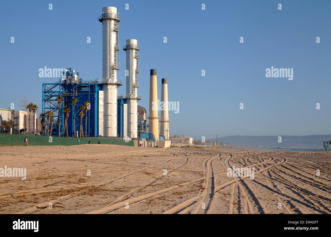 Menschen, die Fahrrad fahren in der Nähe von El Segundo Energiezentrum: ein Industriekraftwerk am Strand von Manhattan Beach, Kalifornien, USA Stockfoto