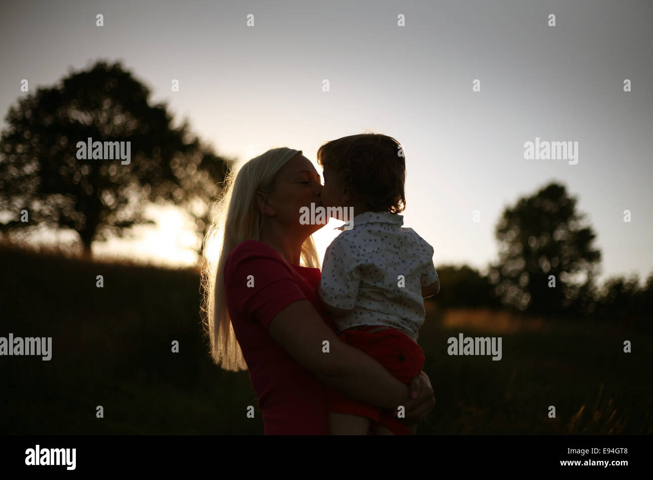 Mama hält Baby Boy bei Sonnenuntergang Stockfoto