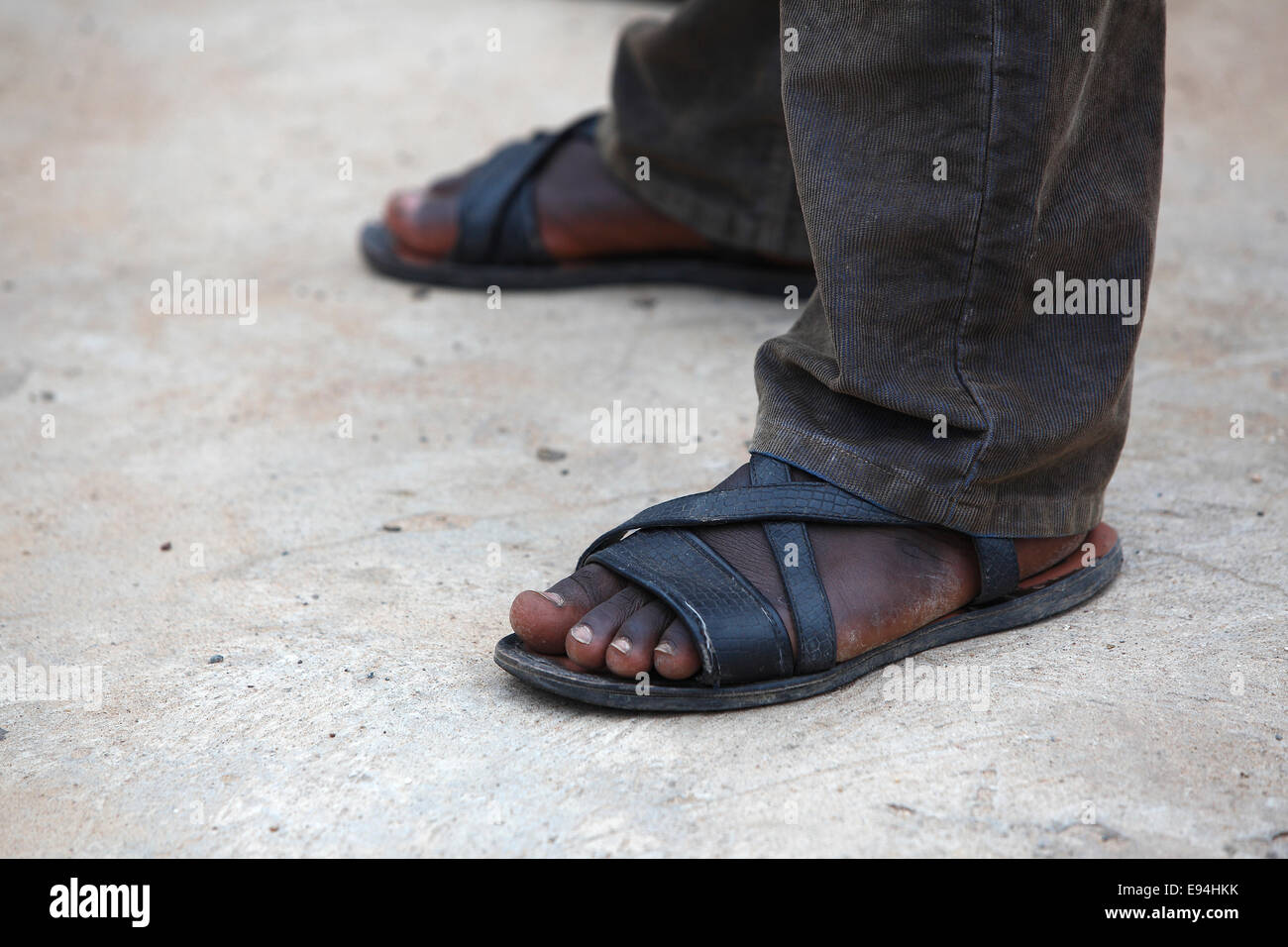 Füße von einem afrikanischen Mann mit langen braunen Hosen Stockfoto