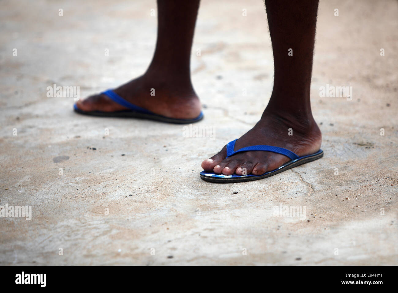 Füße von einem afrikanischen Mann in blau Flip flops auf steinigem Untergrund Stockfoto