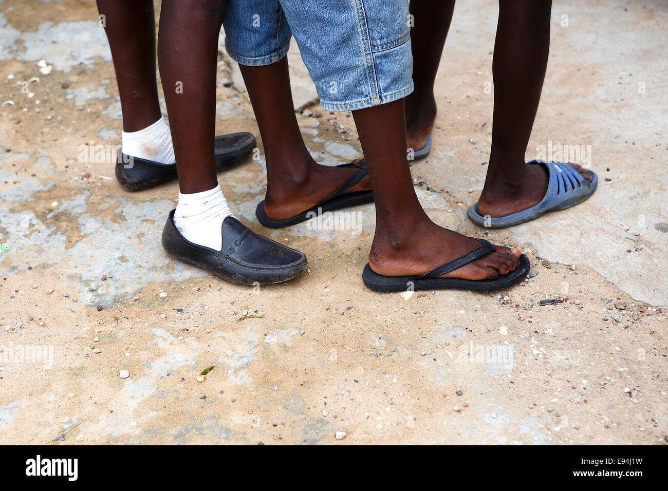 Füße von afrikanischen Männern in verschiedenen Schuhen wartet auf steinigem Untergrund Stockfoto