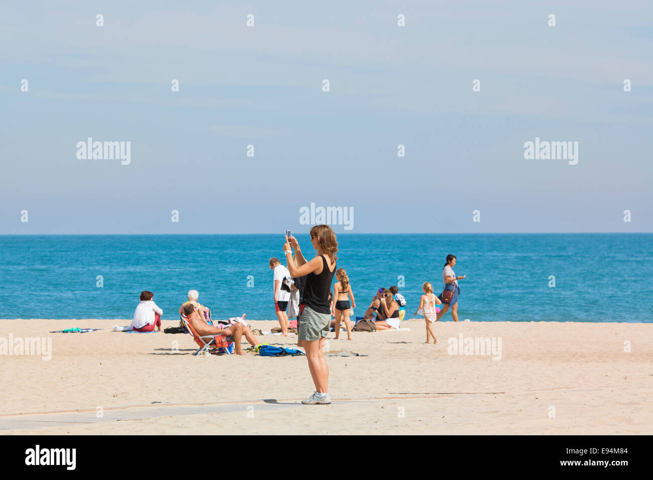 Frau am Strand mit Handy, fotografieren Stockfoto