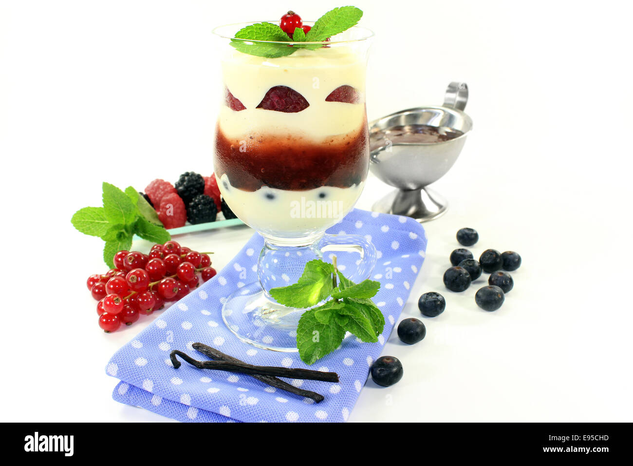 ein Dessert in ein Glas geschichtet mit Pudding, rote Kompott und Beeren Stockfoto