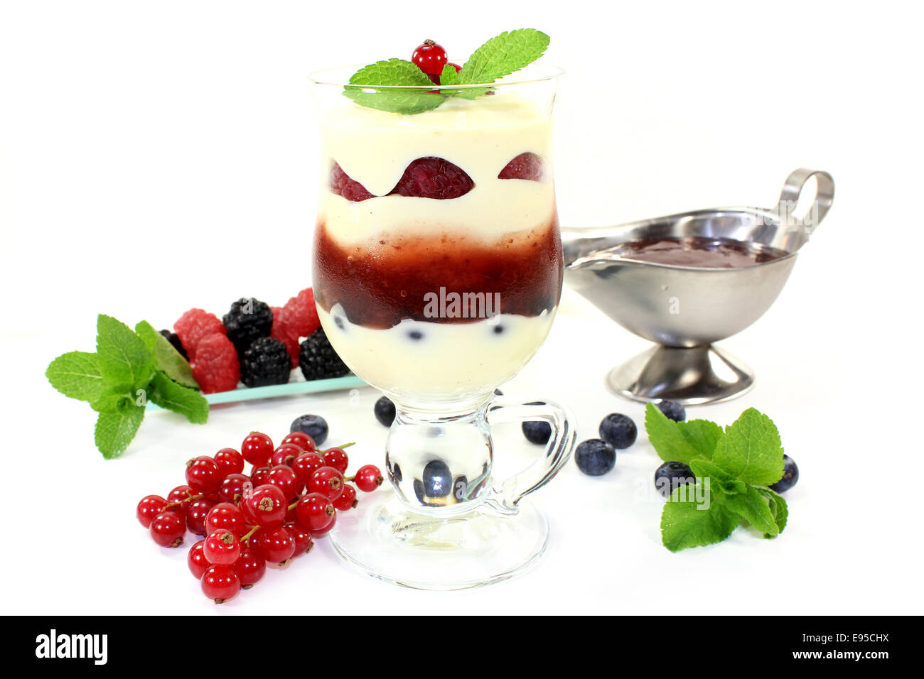 ein Dessert in ein Glas geschichtet mit Pudding, rote Kompott und Beeren Stockfoto