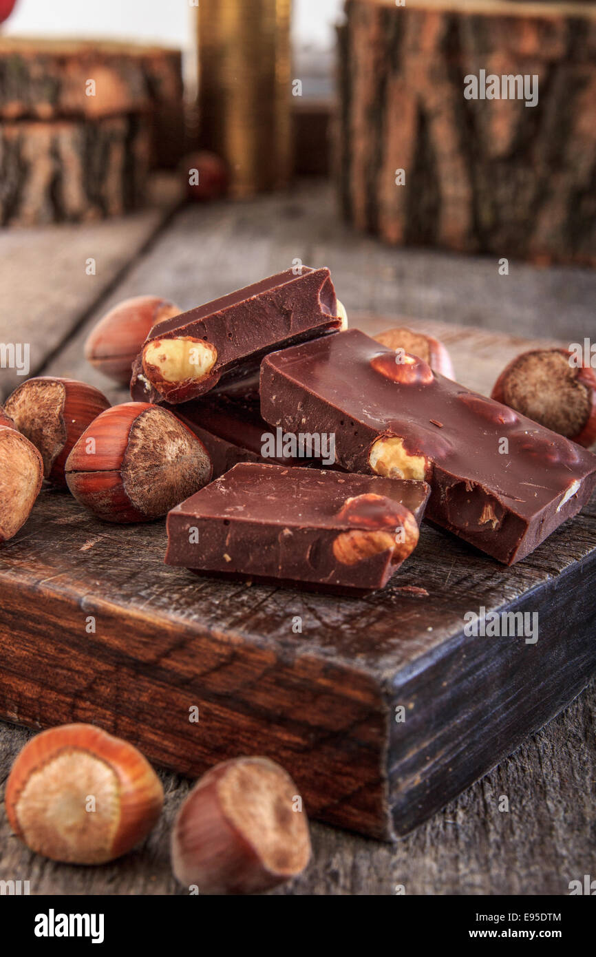 Schokolade mit Nüssen auf hölzernen Hintergrund, Nahaufnahme Detail Schokolade Teile mit Haselnüssen Stockfoto