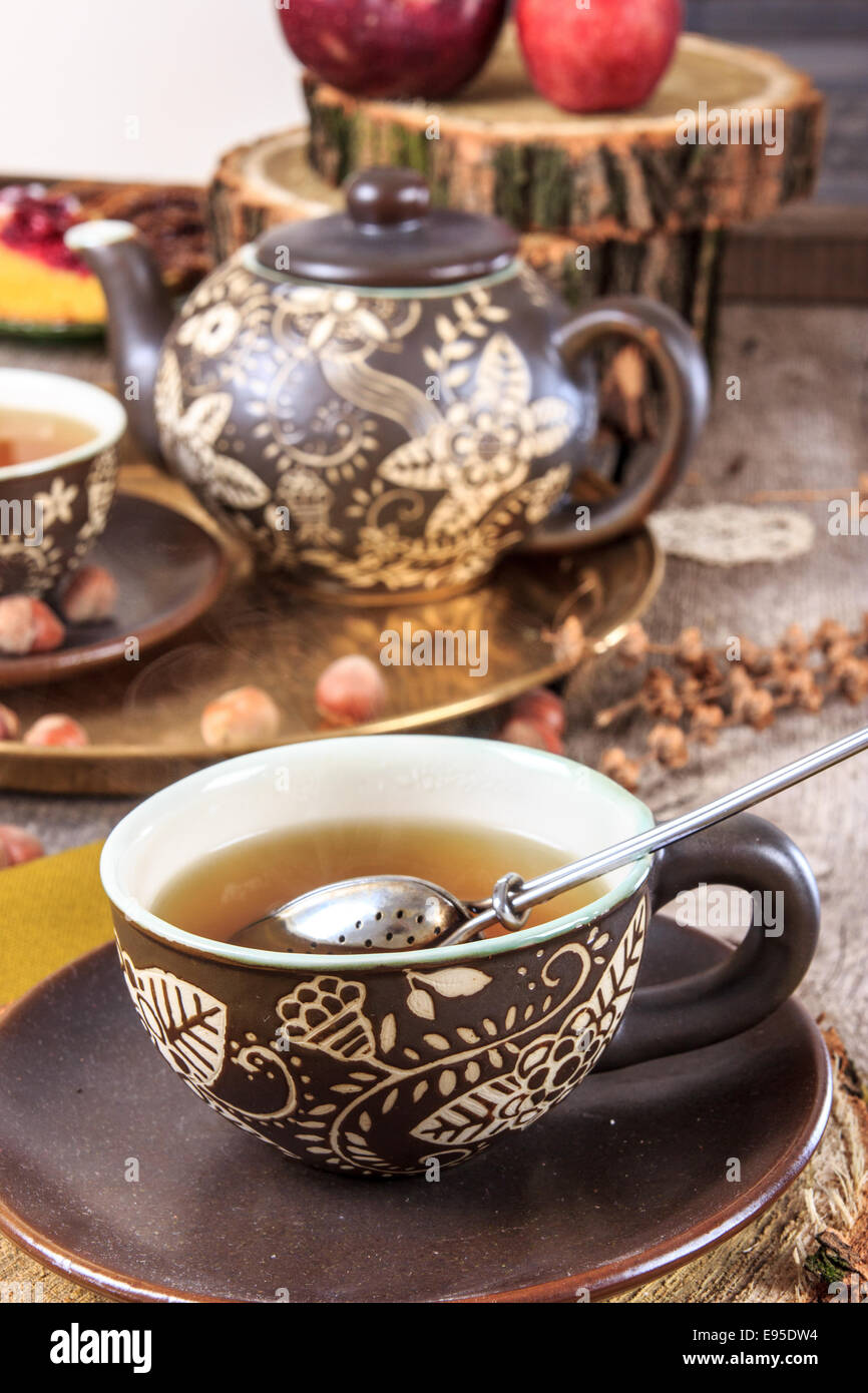 Tasse Tee mit Wasserkocher und Sieb im alten Vintage-Stil auf Holztisch Stockfoto