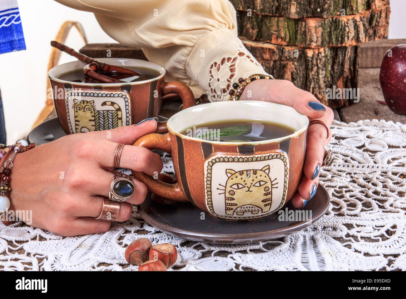 Mädchen hält heiße Tasse Tee auf Holztisch mit Deckchen in alten Vintage Haus Stockfoto