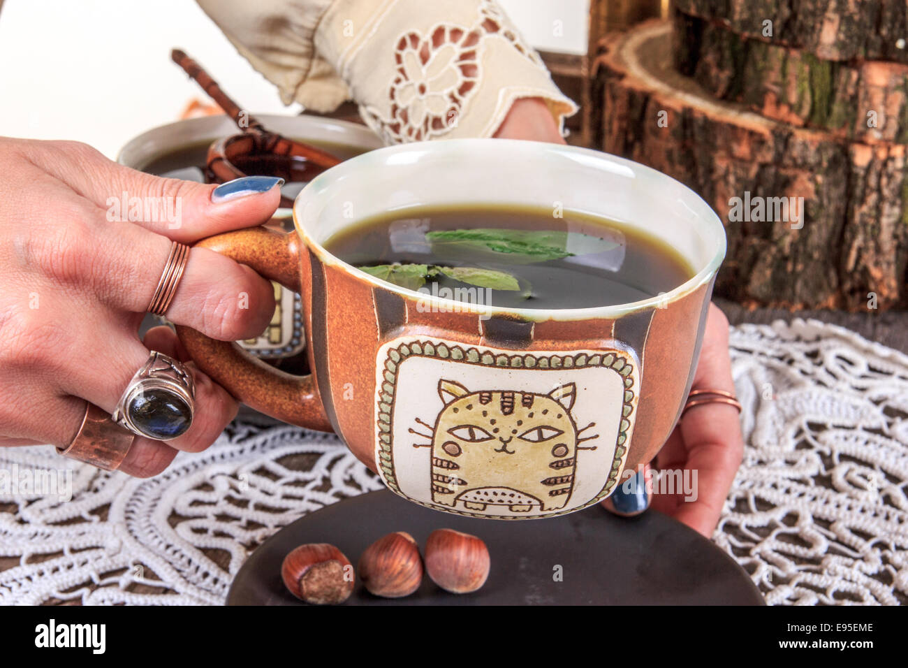 Hände, die traditionelle Holztisch mit Deckchen Teetasse aufsetzen, im alten Stil Stockfoto