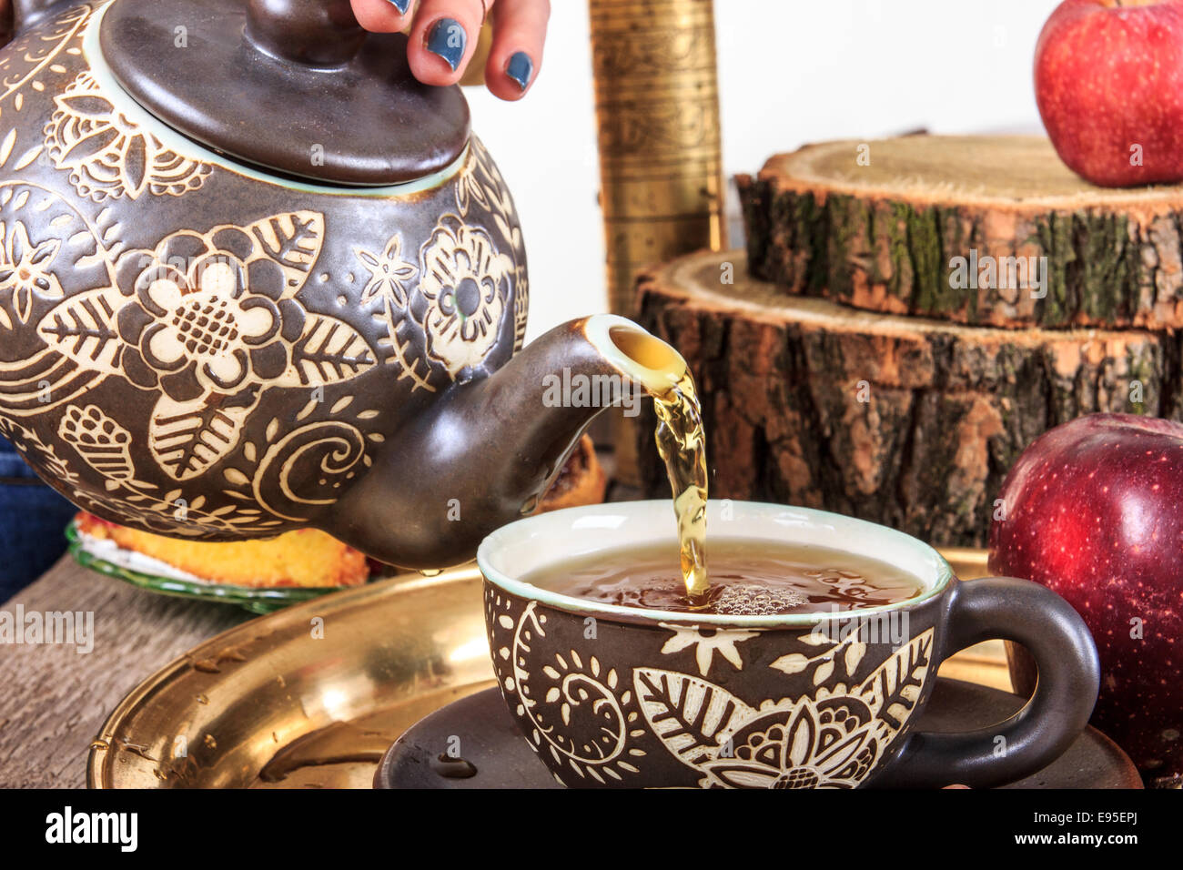 Gießen Tee aus Kessel auf alten Holztisch mit Obst und hausgemachte Kekse Stockfoto