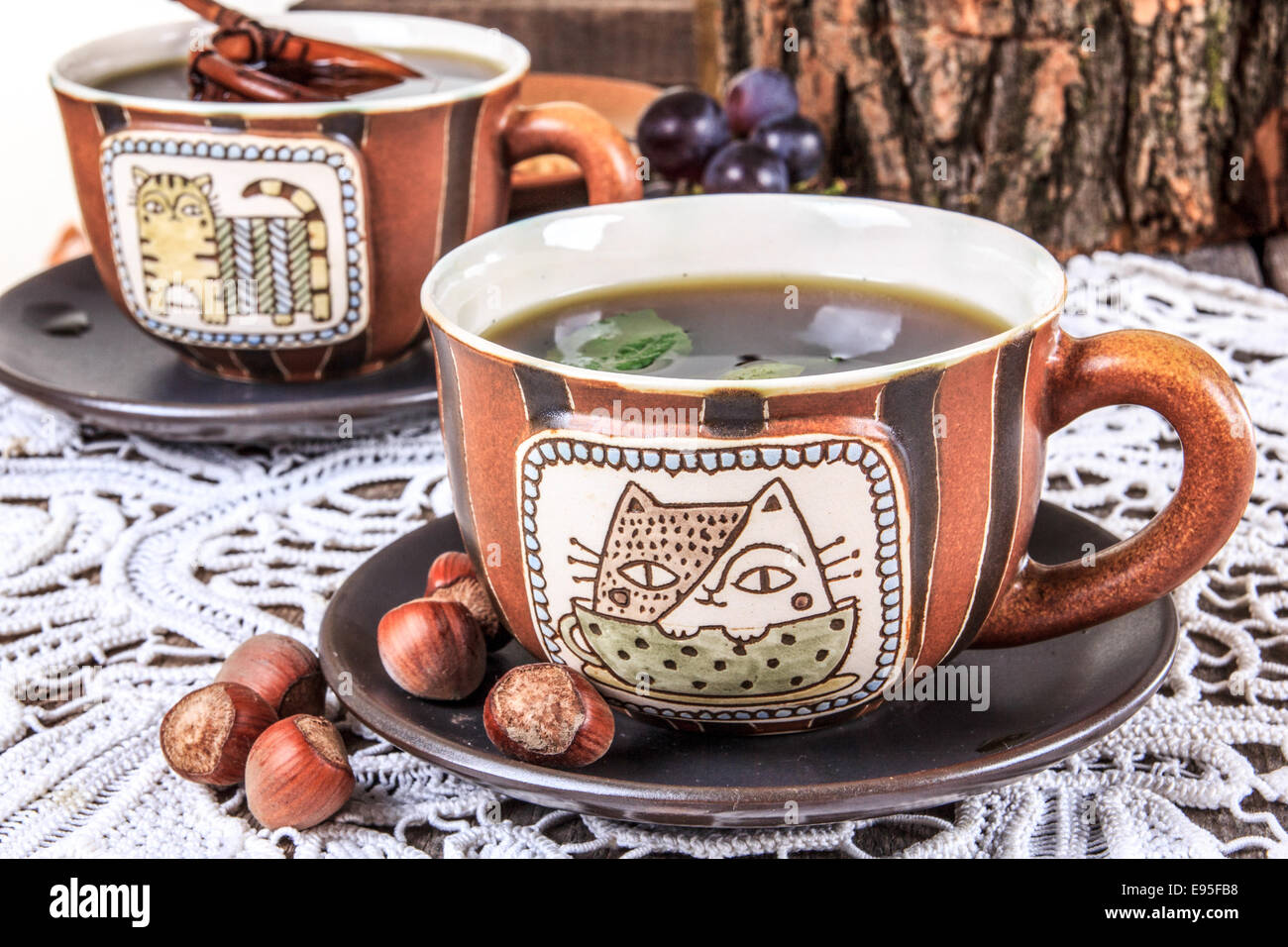 Tee Tasse Zusammensetzung am alten Holztisch mit Deckchen und Haselnüssen Stockfoto