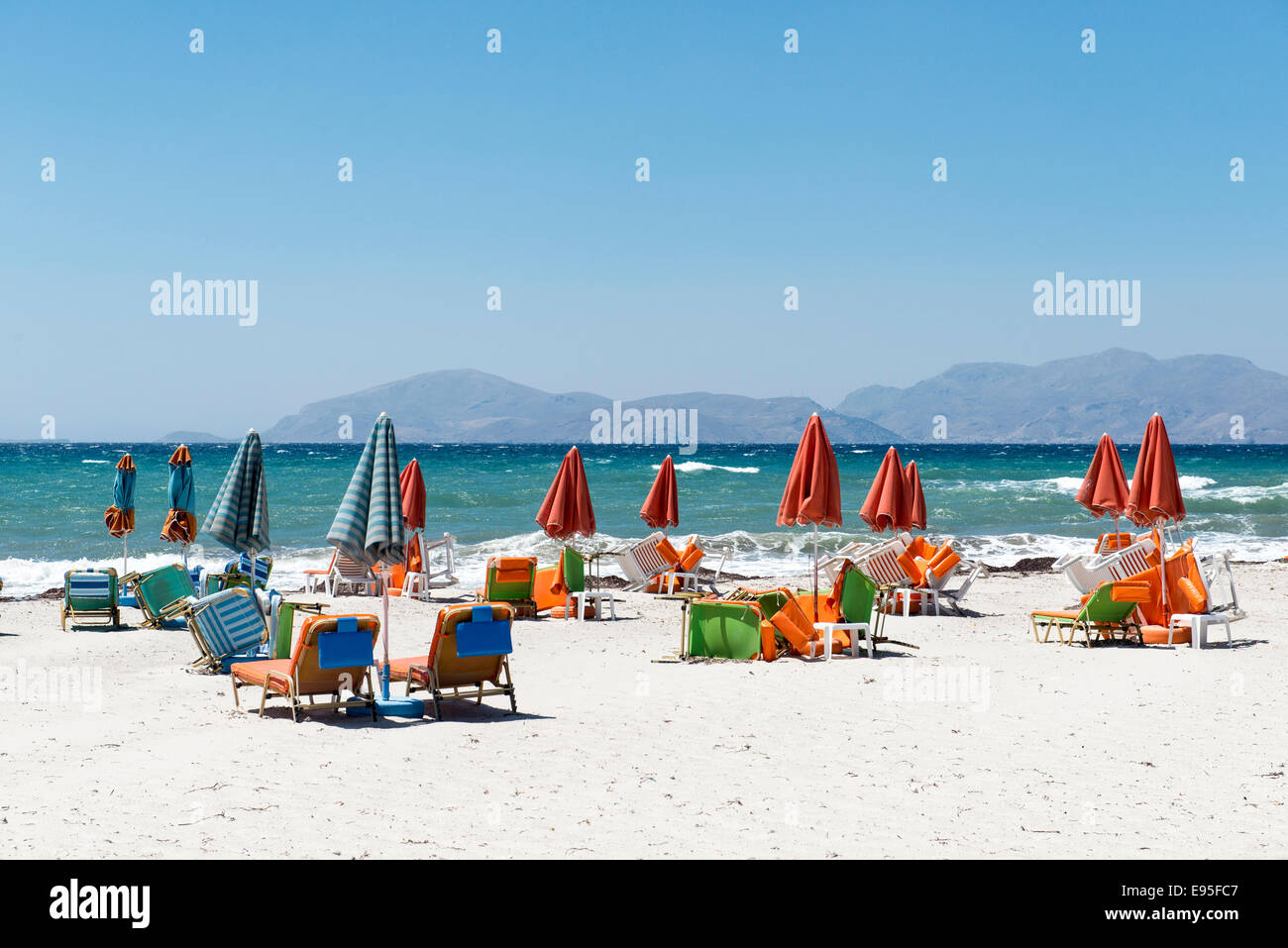 Leeren Strand mit geschlossenen Sonnenschirme und Liegestühle am Strand von Mastichari, Insel Kos, Griechenland Stockfoto
