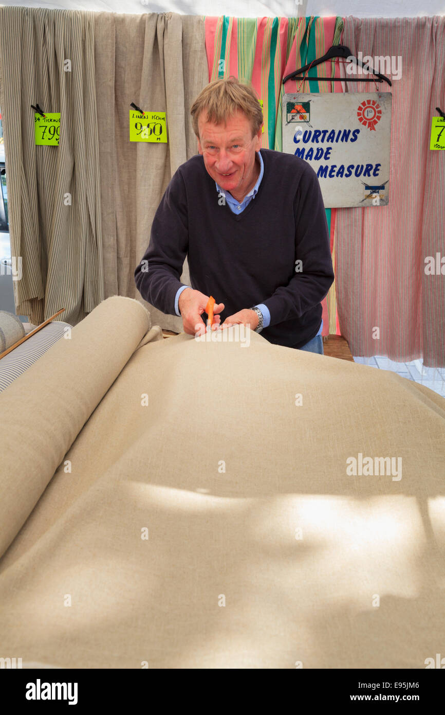 Stoffe Stall Markt Händler schneiden Tuch von der Rolle Stockfoto