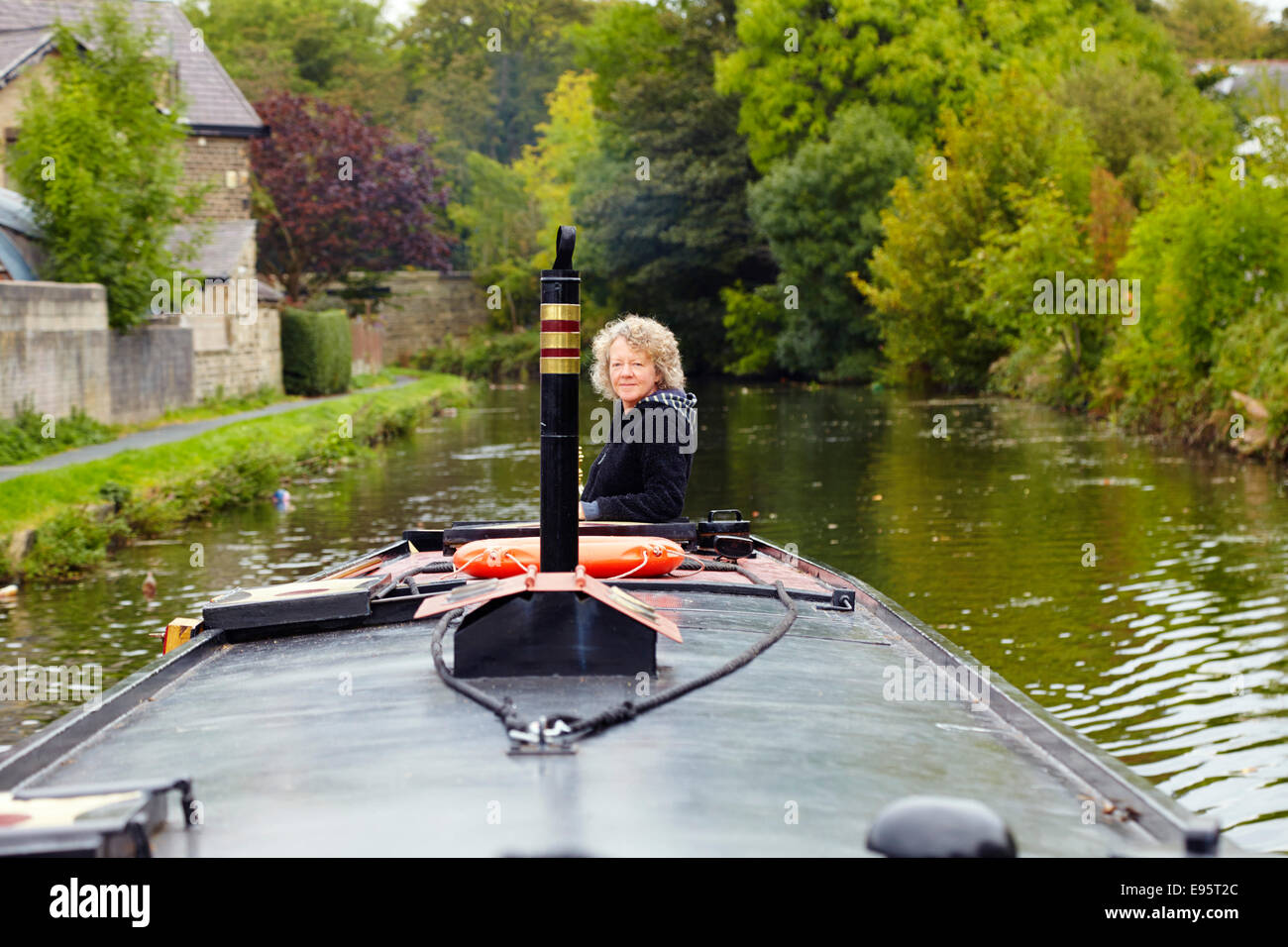 Frau, die Lenkung ein Narrowboat auf einem Kanal Stockfoto