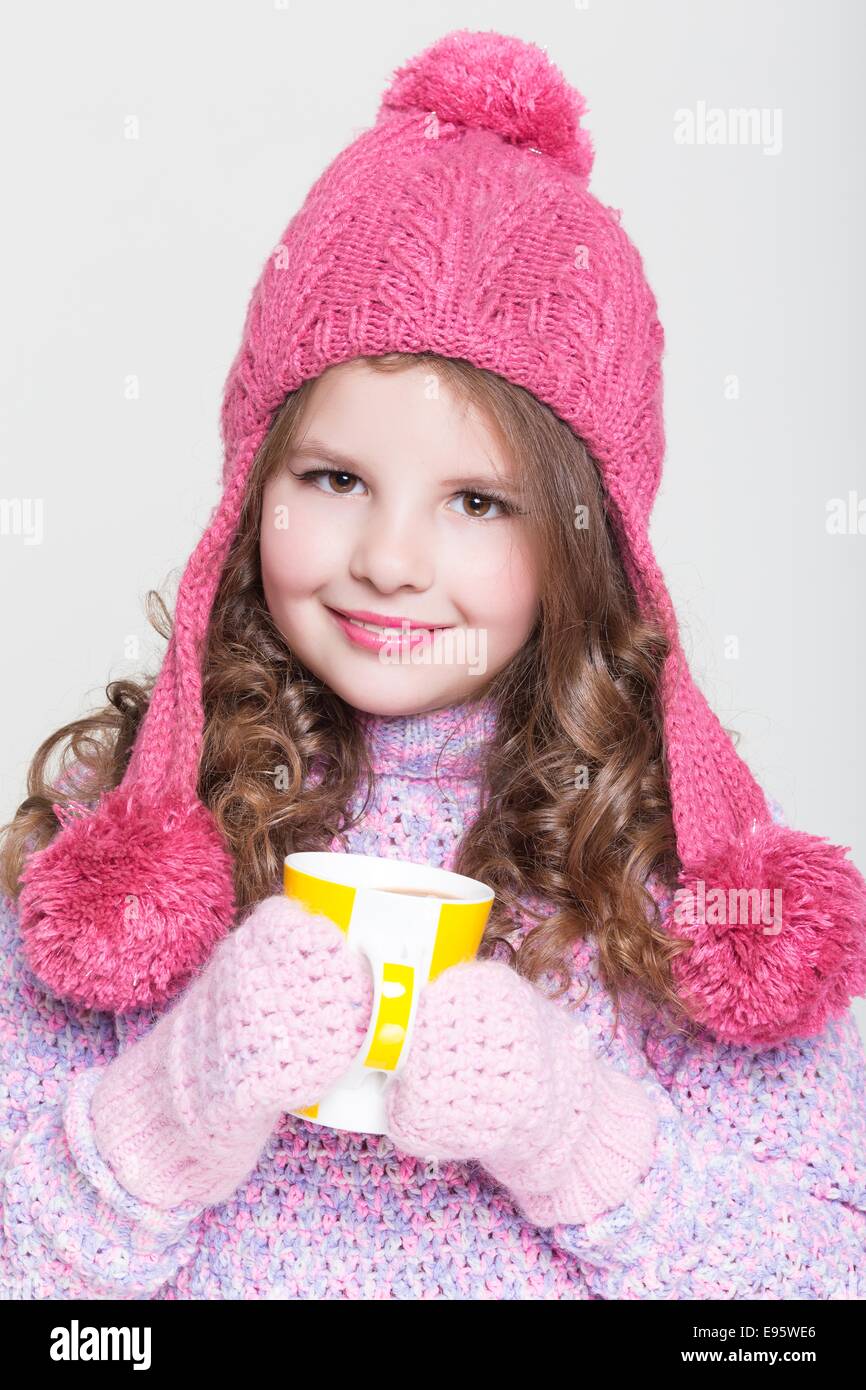 Glückliches kleines Kind in Winterkleidung und heiße Schokolade, süße Babymädchen in Woll Zubehör, Studio, weißen Hintergrund. Stockfoto