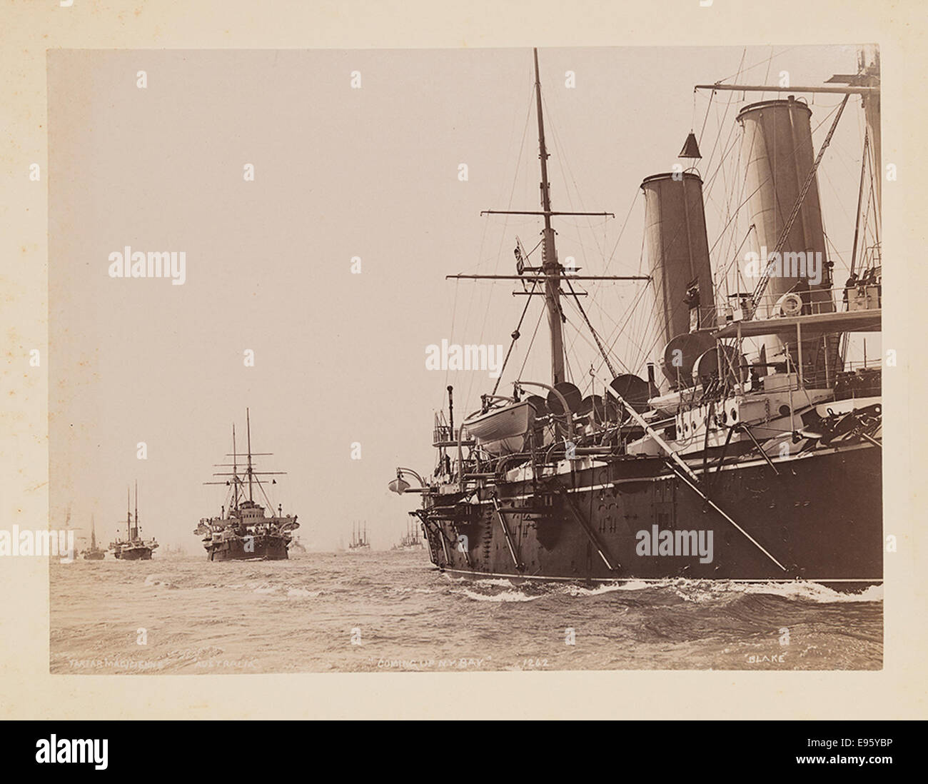 Dieses Foto zeigt ein Schiff, das sich der New York Bay nähert, mit Seeleuten an Deck. Die Flaggen des Schiffes fliegen, und die Takelage des Schiffes ist im Schuss deutlich sichtbar. Es fängt einen Moment während einer Reise in den geschäftigen Hafen von New York ein. Stockfoto