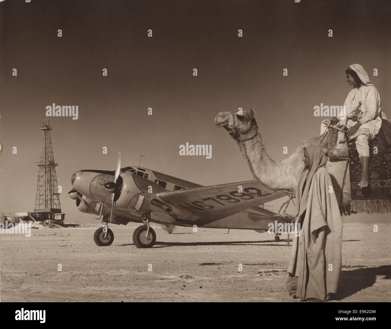 [Ölquelle Bohranlage in Wüste mit Flugzeug und Männer mit Kamel, Arabian American Oil Co., Saudi-Arabien genommen] Stockfoto