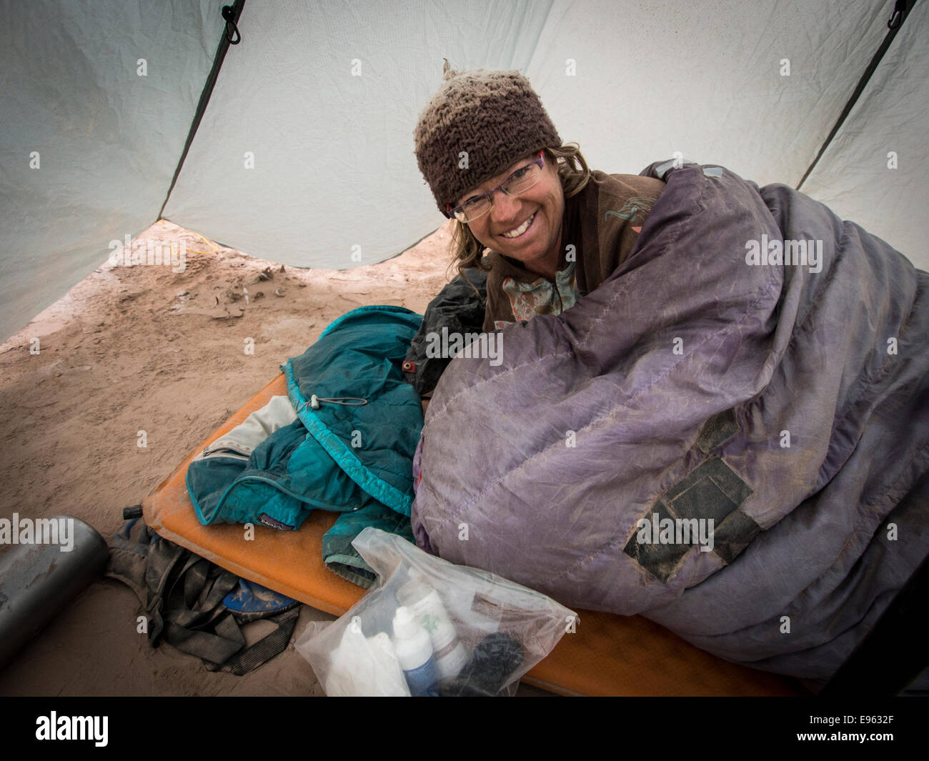 Suzy Loeffler lächelt in die Kamera von ihrem schmutzigen Schlafsack während unter einer Plane, Utah lagerten. Stockfoto