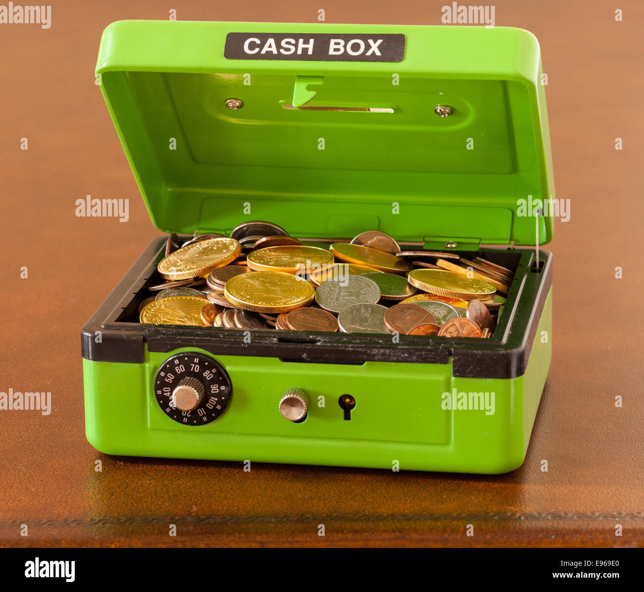 Grüne Kasse mit Gold- und Silbermünzen Stockfoto