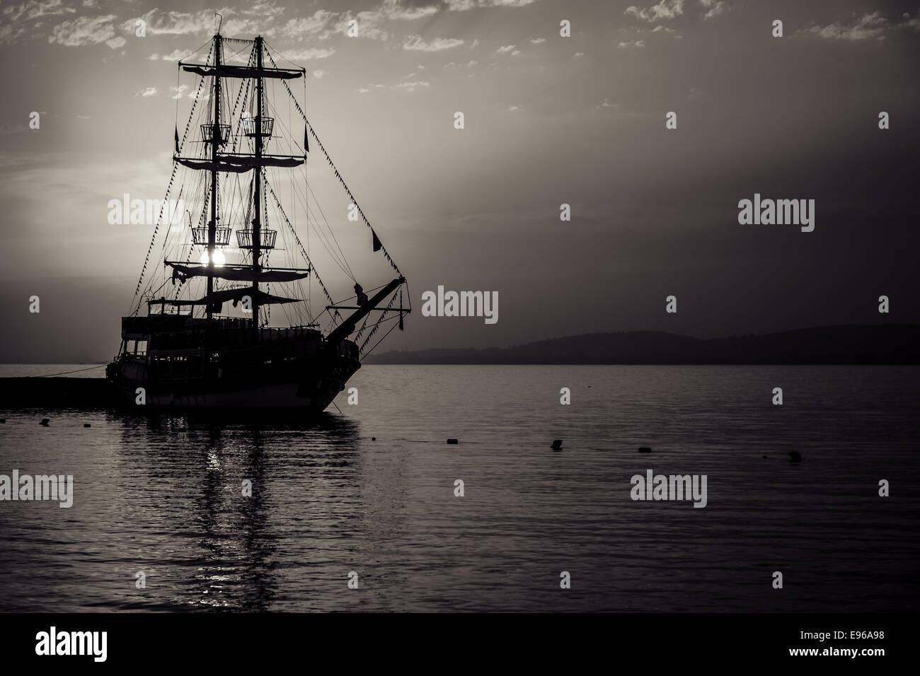 Sonnenuntergang über dem Meer und ein einsamer Segelschiff in der Bucht. Stilisierung. Tonen. Sepia. Stockfoto