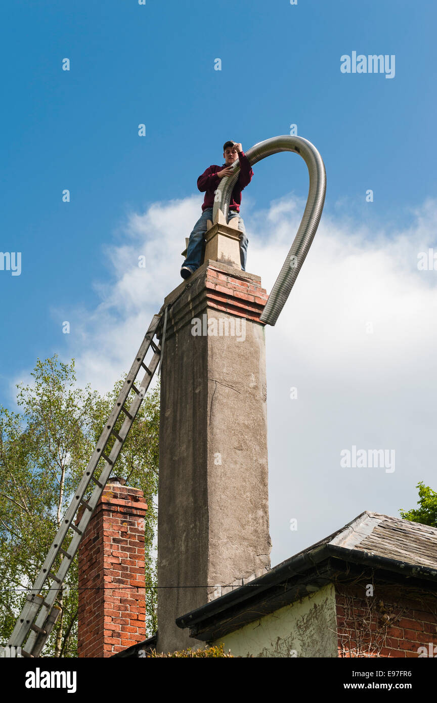 Einfügen einer flexiblen Kamineinsatzrohr in den Schornstein eines alten Hauses, UK Stockfoto