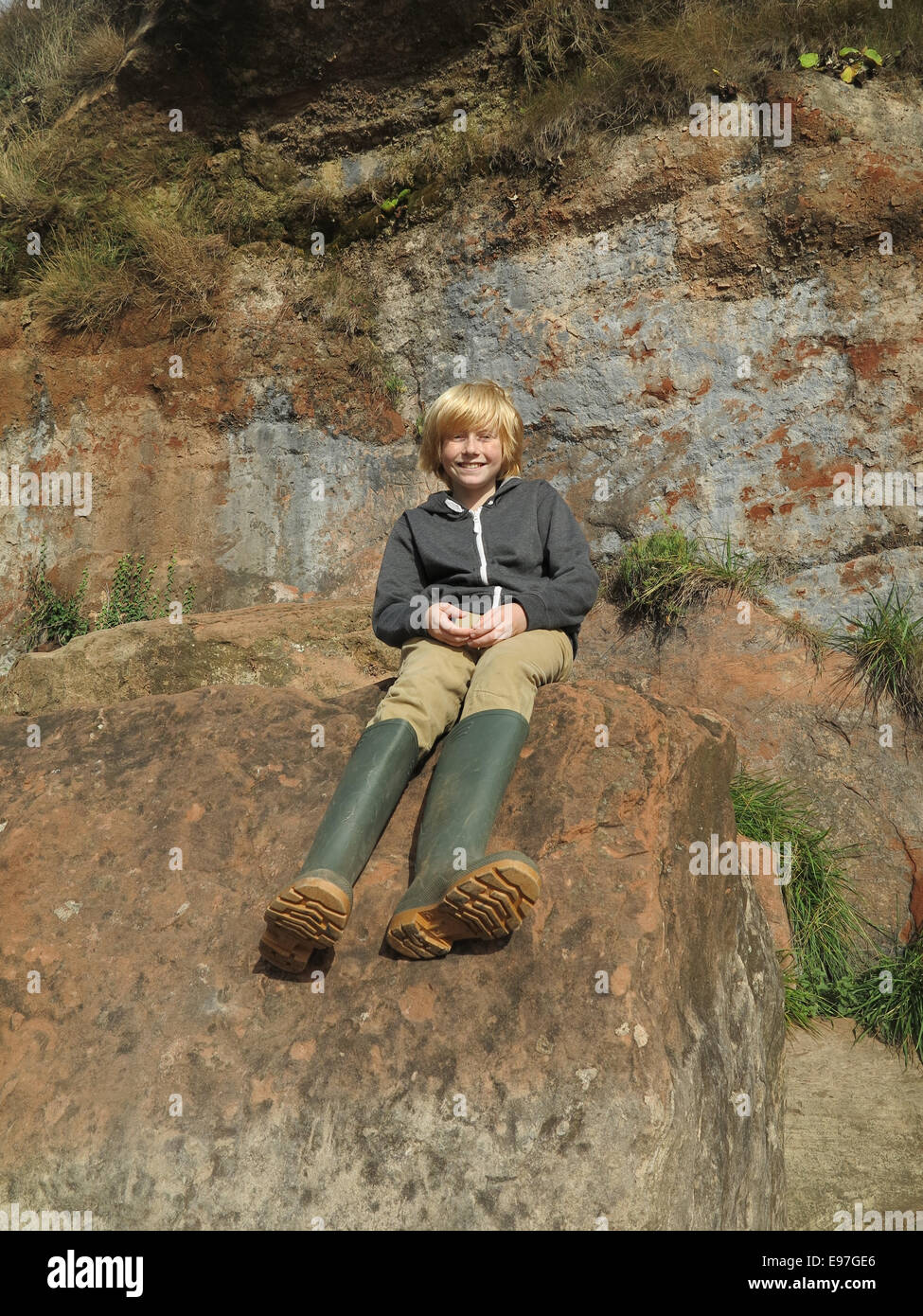 Junge saß auf Felsen Stockfoto