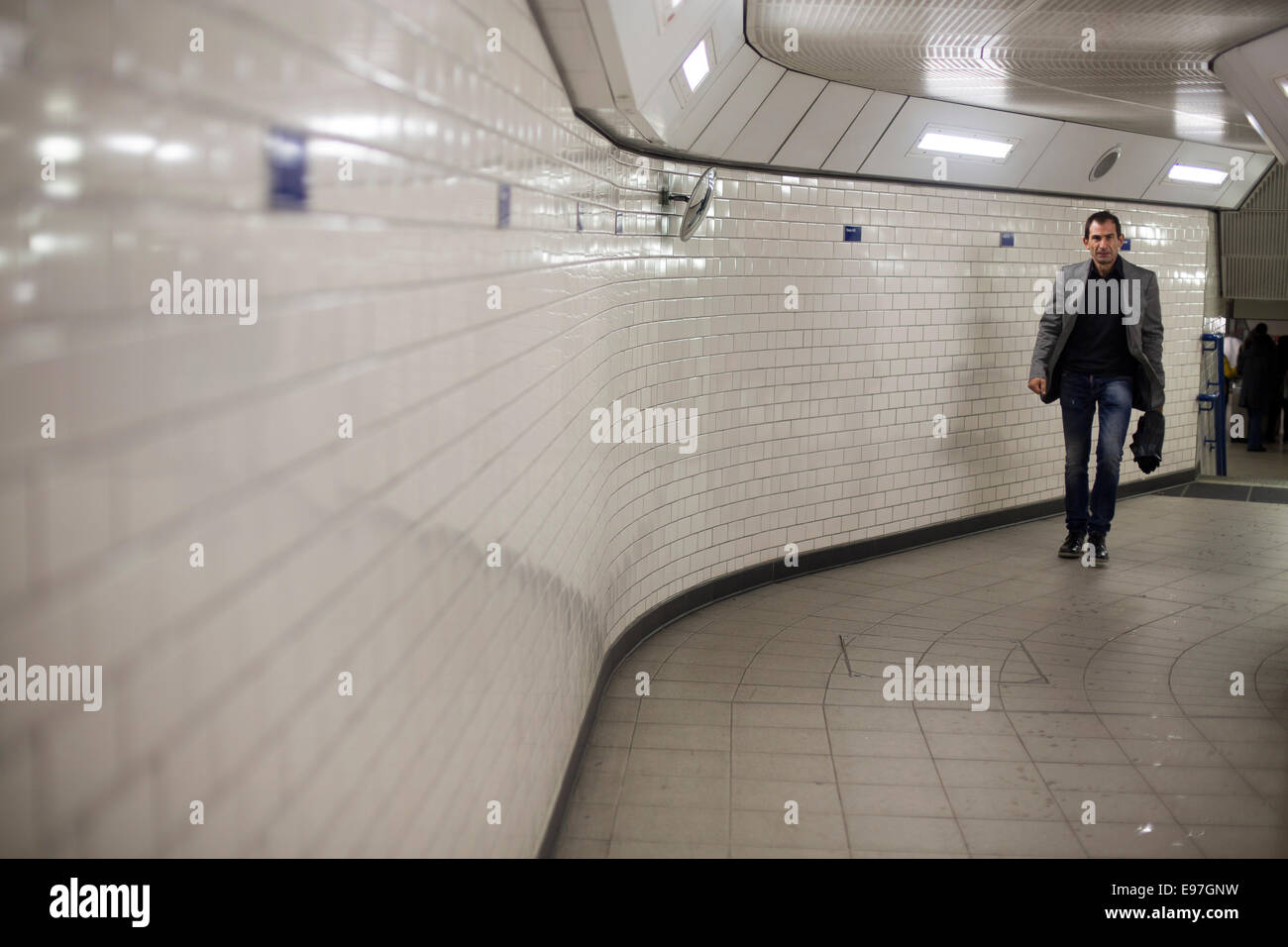 Mann am Rohr im u-Bahn Tunnel gefliest Stockfoto