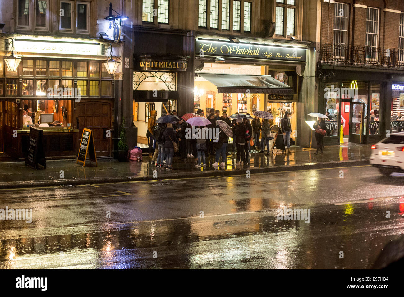 Massen auf nasser Straße Nacht der Whitehall Pub Regen Stockfoto