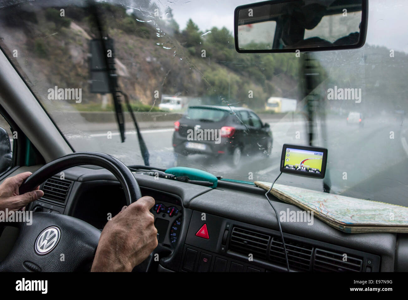 Rasende Autos überholen Fahrzeug auf der Autobahn während starkem Regendusche im Inneren Autos mit GPS und Fahrplan auf Armaturenbrett aus gesehen Stockfoto