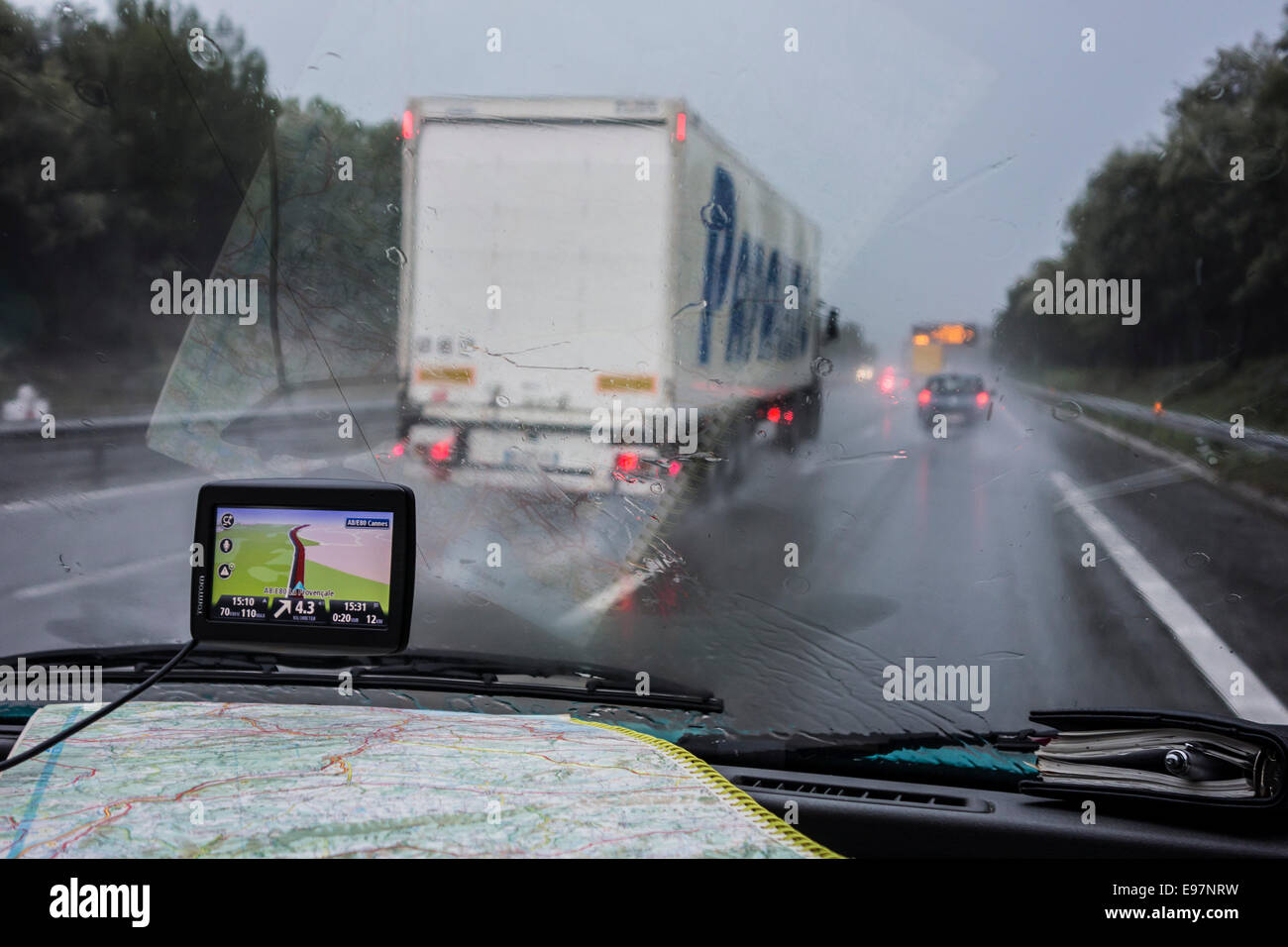 Rasende Lkw Autos auf der Autobahn überholen während starkem Regendusche im Inneren Autos mit GPS und Fahrplan auf Armaturenbrett aus gesehen Stockfoto