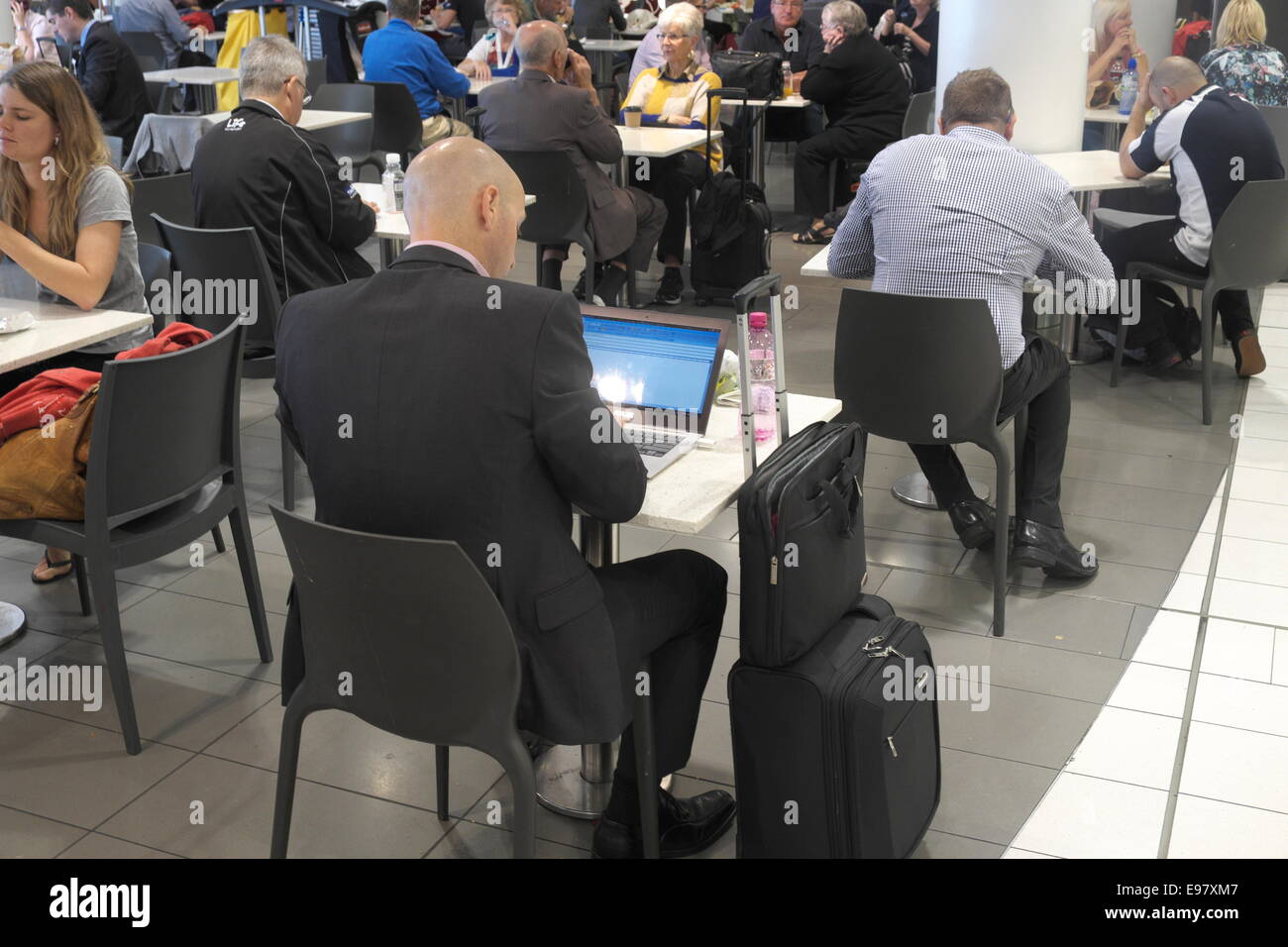 Geschäftsmann auf Laptop am Sydney Flughafen Abflughalle Terminal 2 Halle Viertel mit Geschäften und Restaurants, New South Wales, Australien Stockfoto
