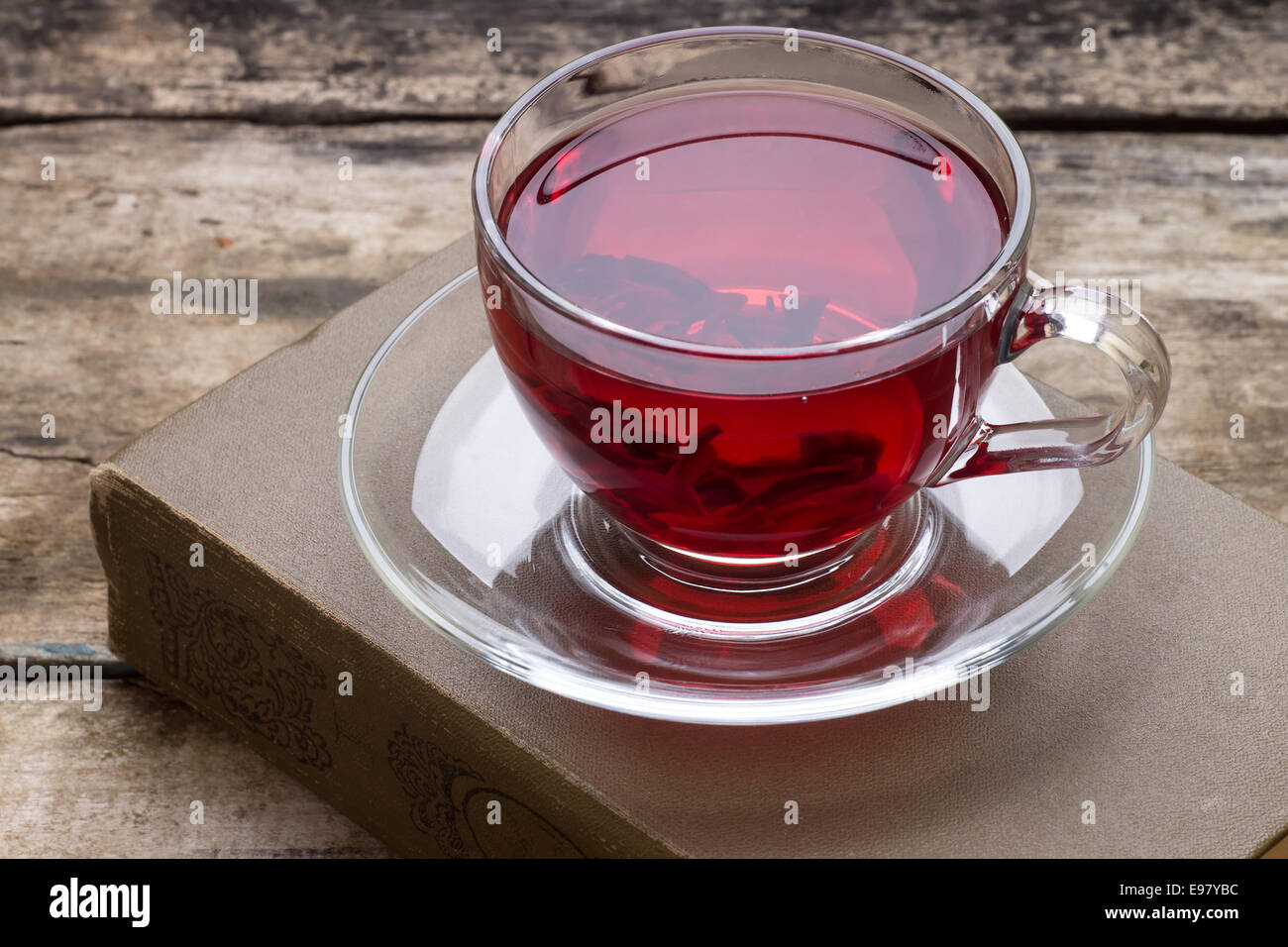 Tasse rot Karkade Tee mit Buch auf hölzernen Hintergrund Stockfoto