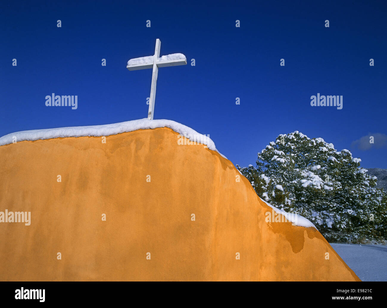 Ein weißes Kreuz auf einem verschneiten Adobe-Wand in Santa Fe, New Mexico Stockfoto