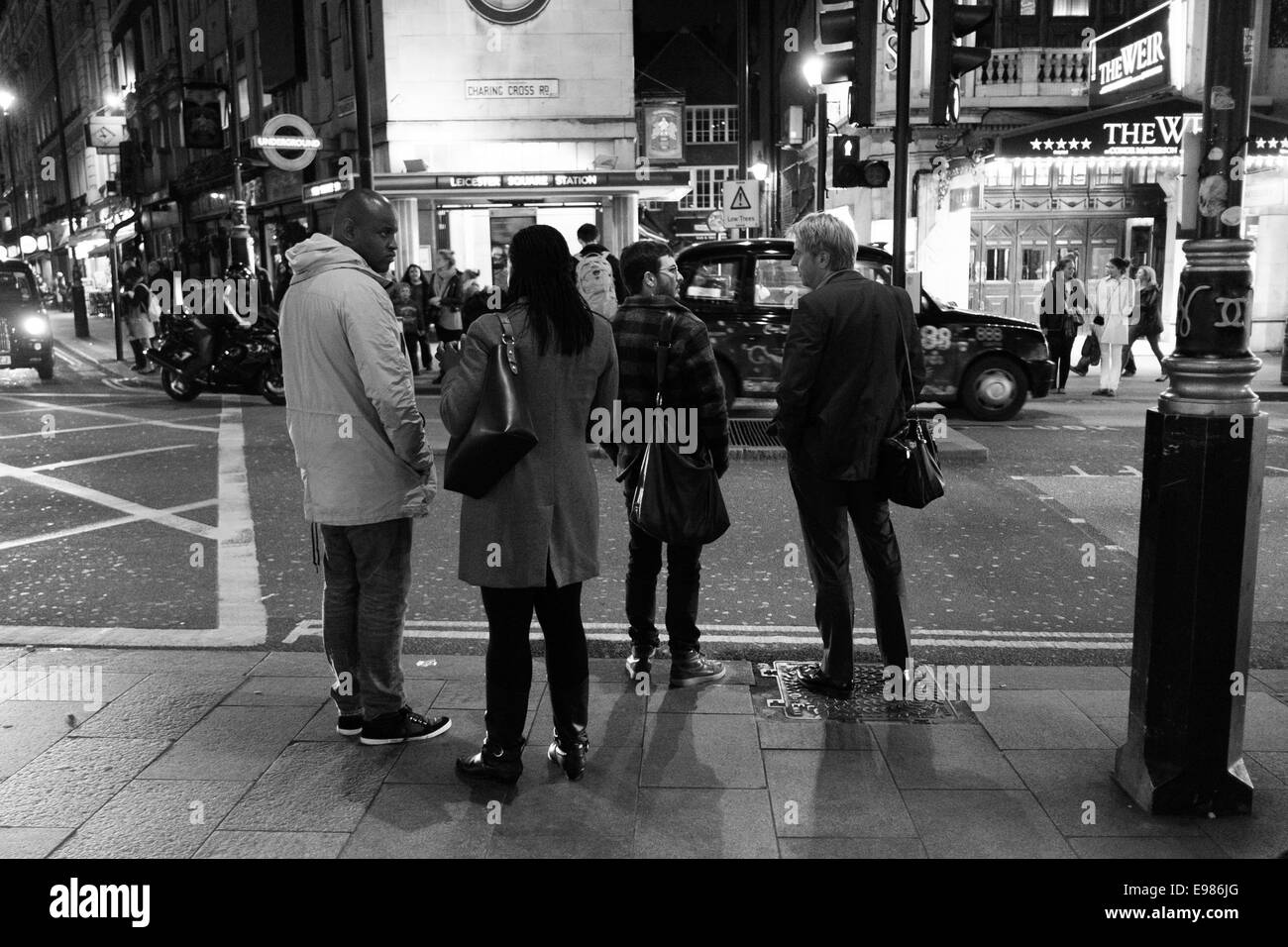 Eine Gruppe von Menschen stehen und reden an einer viel befahrenen Straße-Kreuzung im Zentrum von London.  Schwarz und weiß. Stockfoto