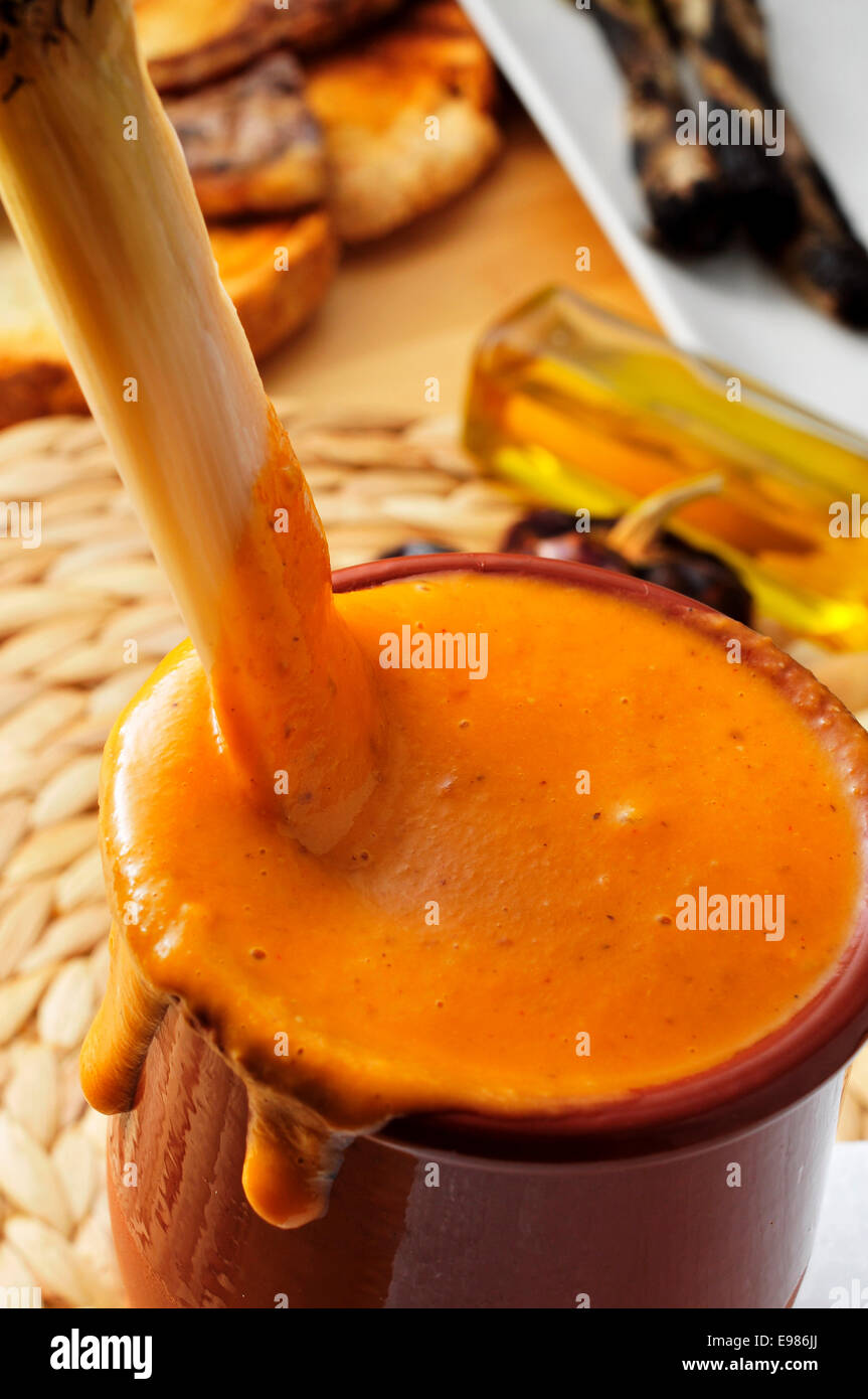 Nahaufnahme von einem gegrillten Calcot, süße Zwiebel, eingetaucht in eine Schüssel mit Romesco-Sauce, typisch für Katalonien, Spanien Stockfoto