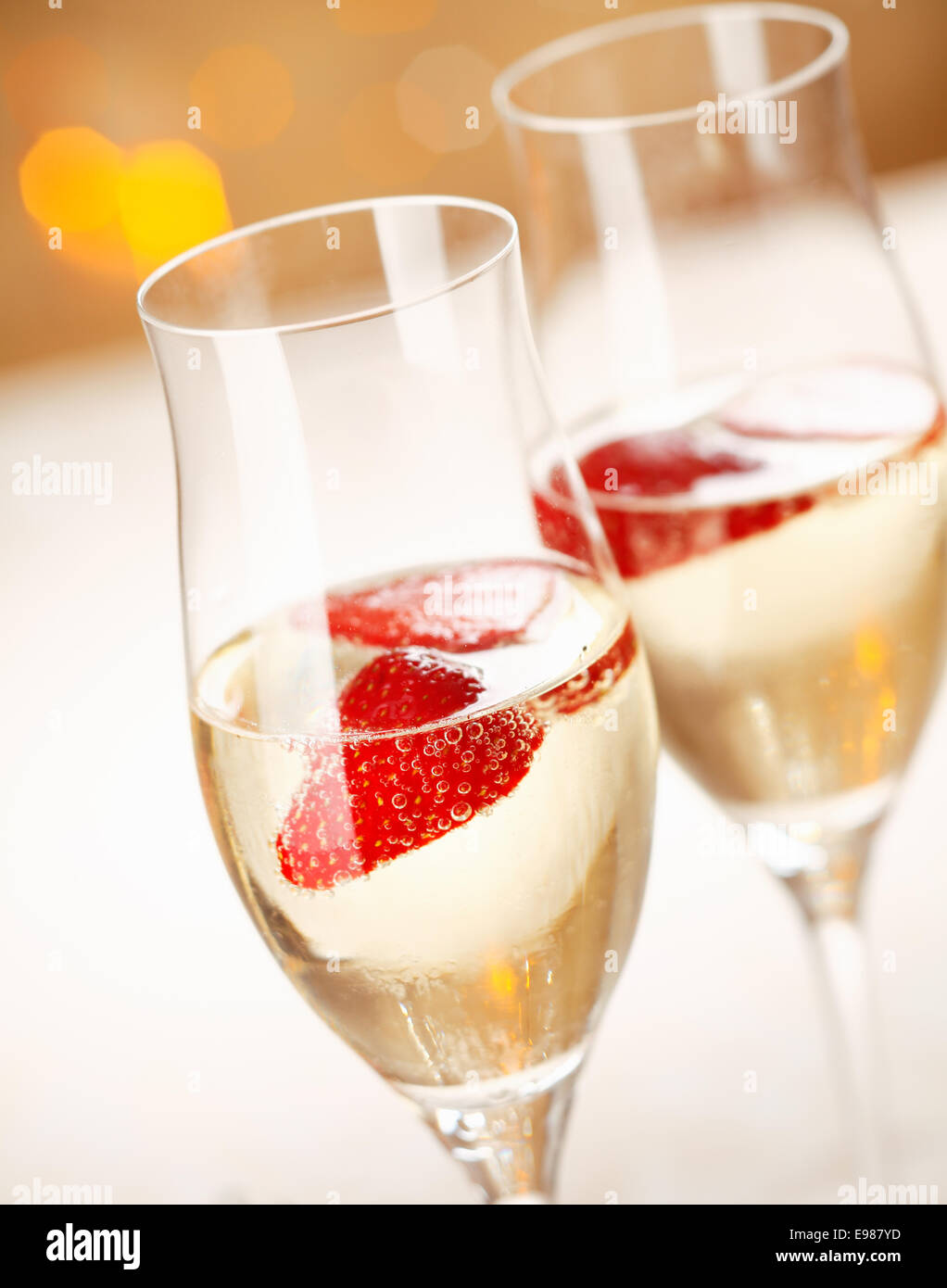 Nahaufnahme der stilvolle Sektgläser gefüllt mit gekühltem Sekt und eine schwimmende Erdbeere für die Feier eines romantisches Abend zu zweit Stockfoto