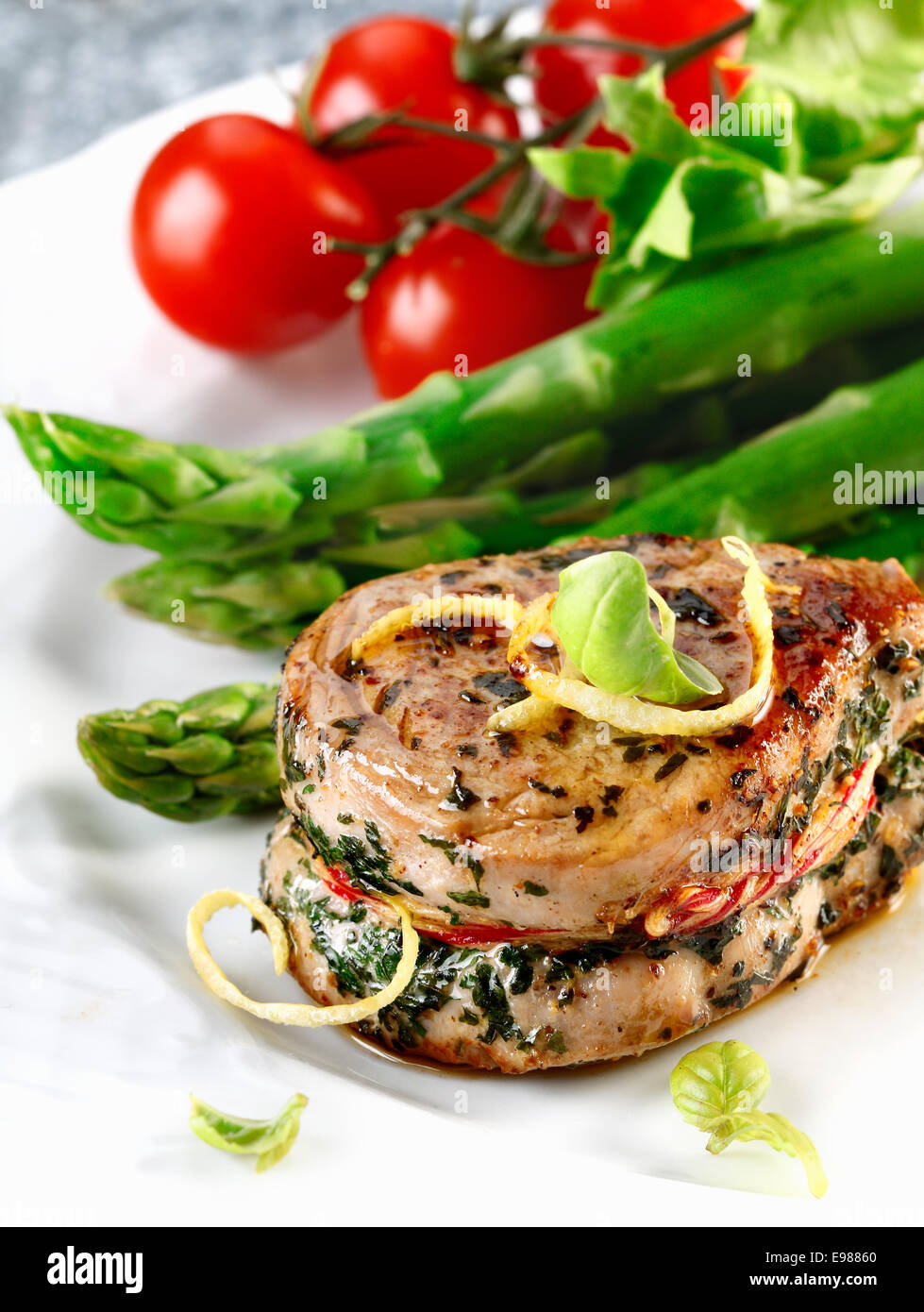 Sirloin-Steak für einen Schweinebraten und Spargel und Tomaten. Frischfleisch Mahlzeit Menü Stockfoto
