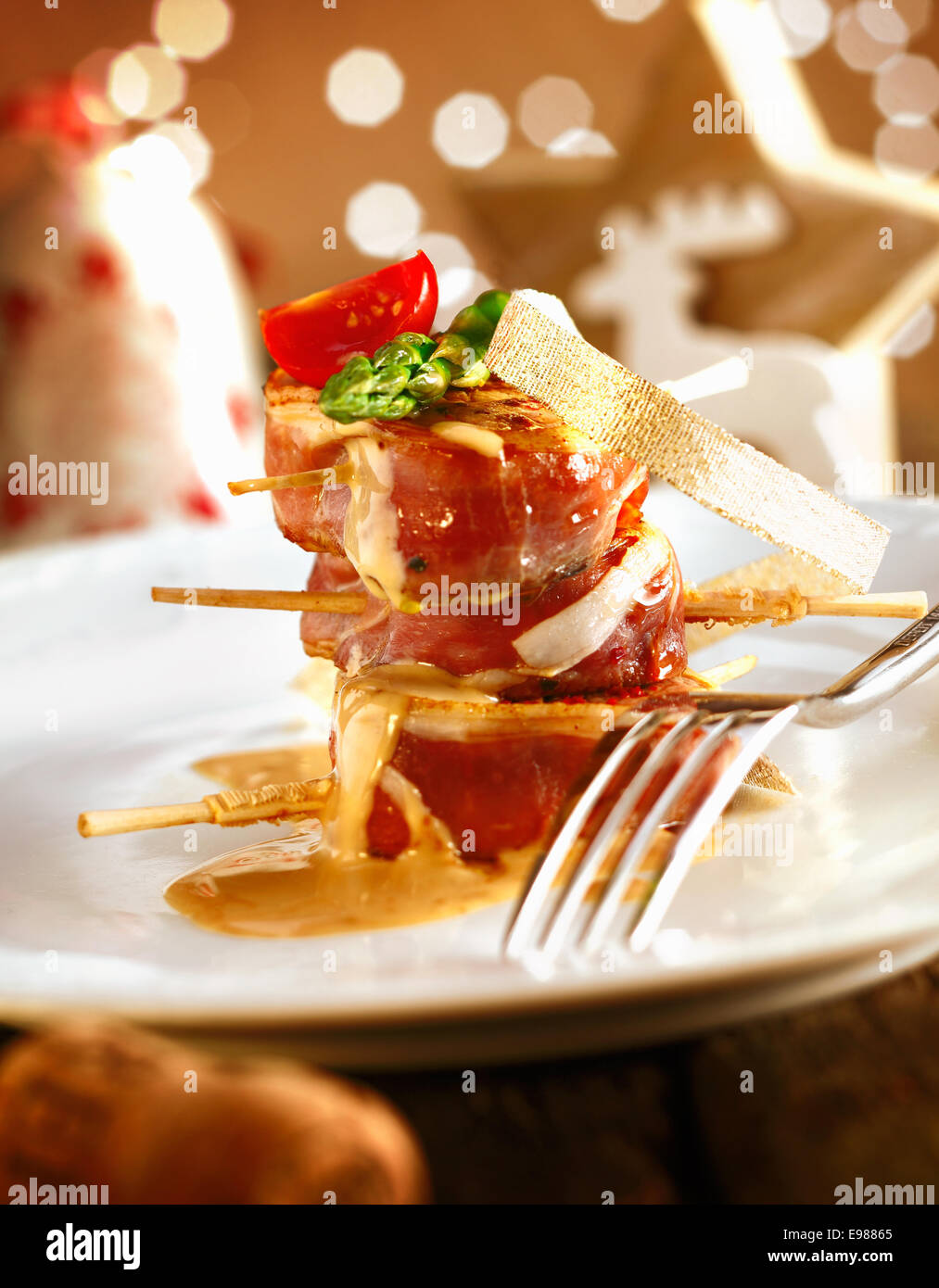 Bankett-Festmahl mit Weihnachtsdekoration. Rotes Fleisch Schweinefilet auf einem weißen Teller mit schönen beleuchtet Boketh Hintergrund des Goldenen Lichts Stockfoto
